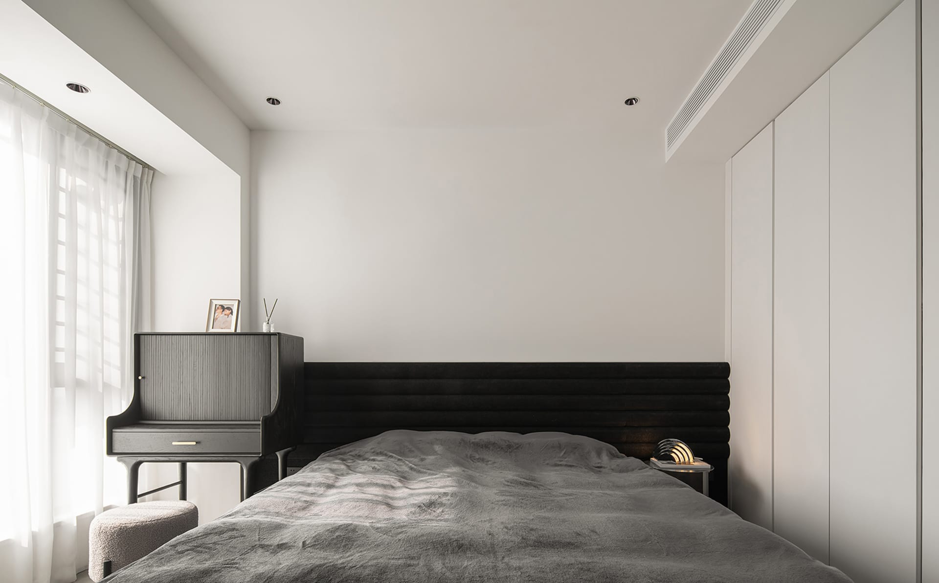 Minimalist bedroom with black furniture and wooden headboard