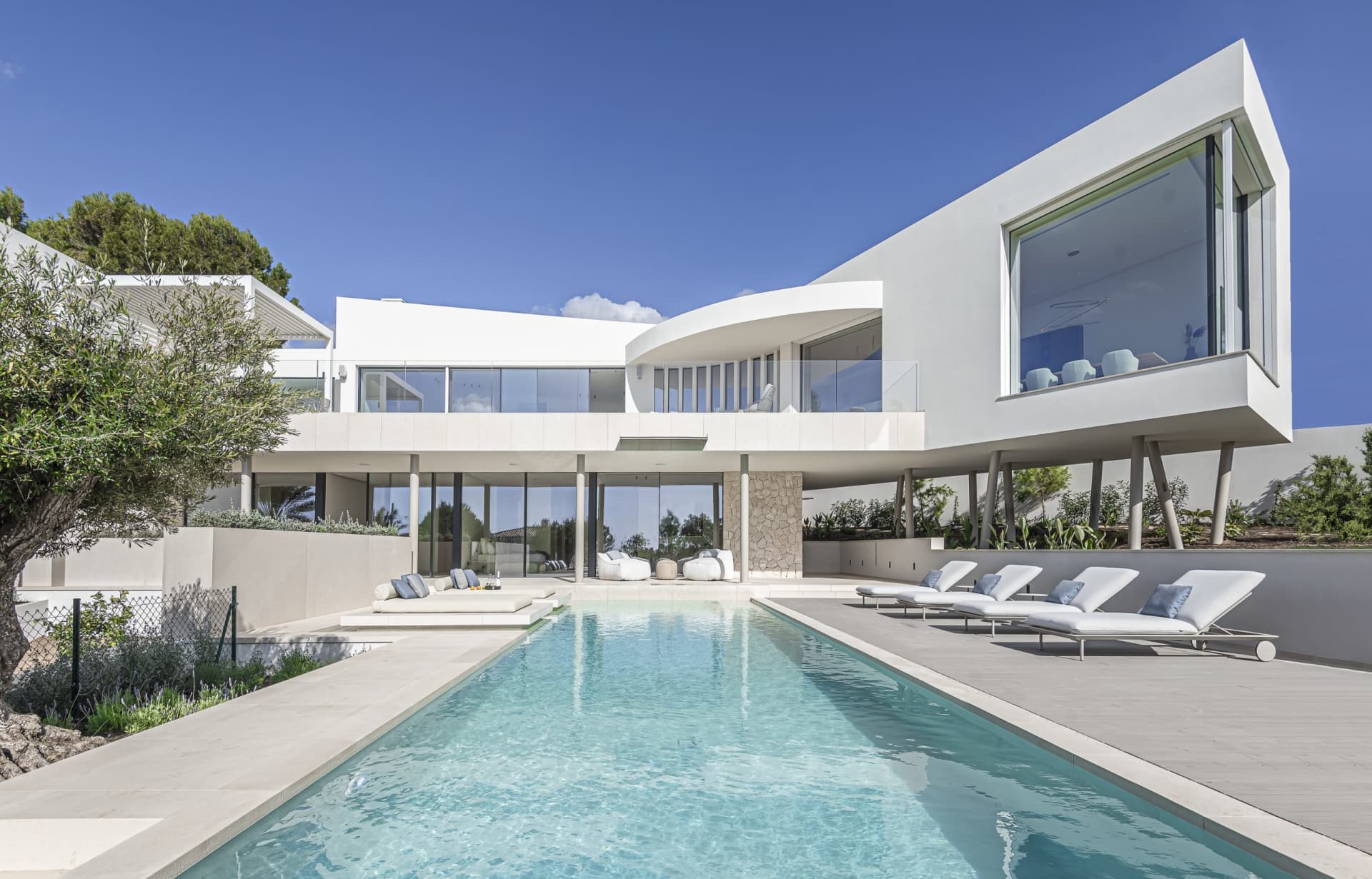 A modern residential pool house featuring glass, concrete, and stone materials.