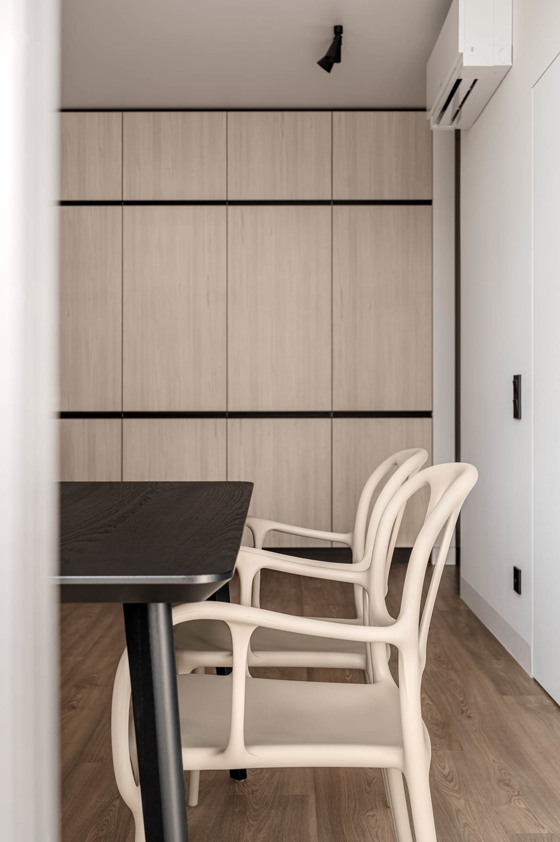 Modern minimalist dining room with wooden furniture and a sleek, dark dining table.