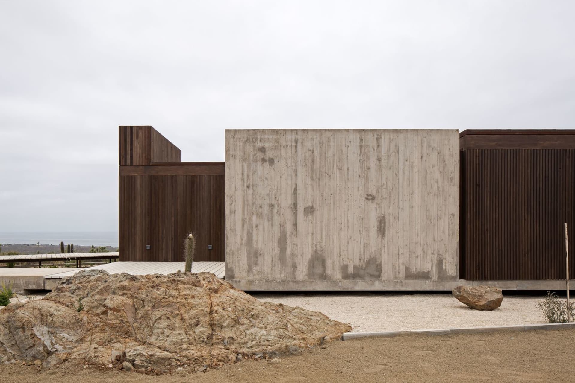 A photograph of a modern house with a minimalist exterior design featuring concrete walls and wood panels.