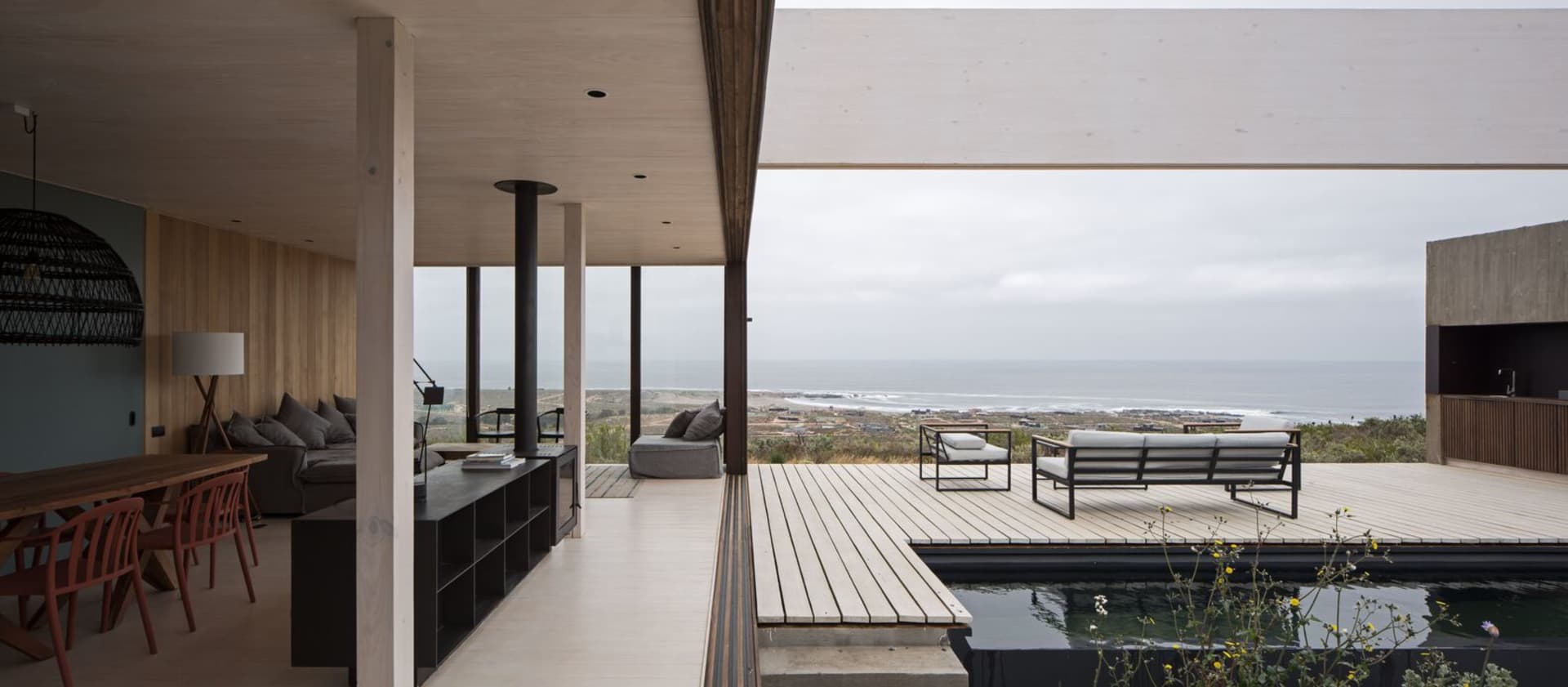 Modern vacation home terrace featuring a wood deck with furniture and ocean view.