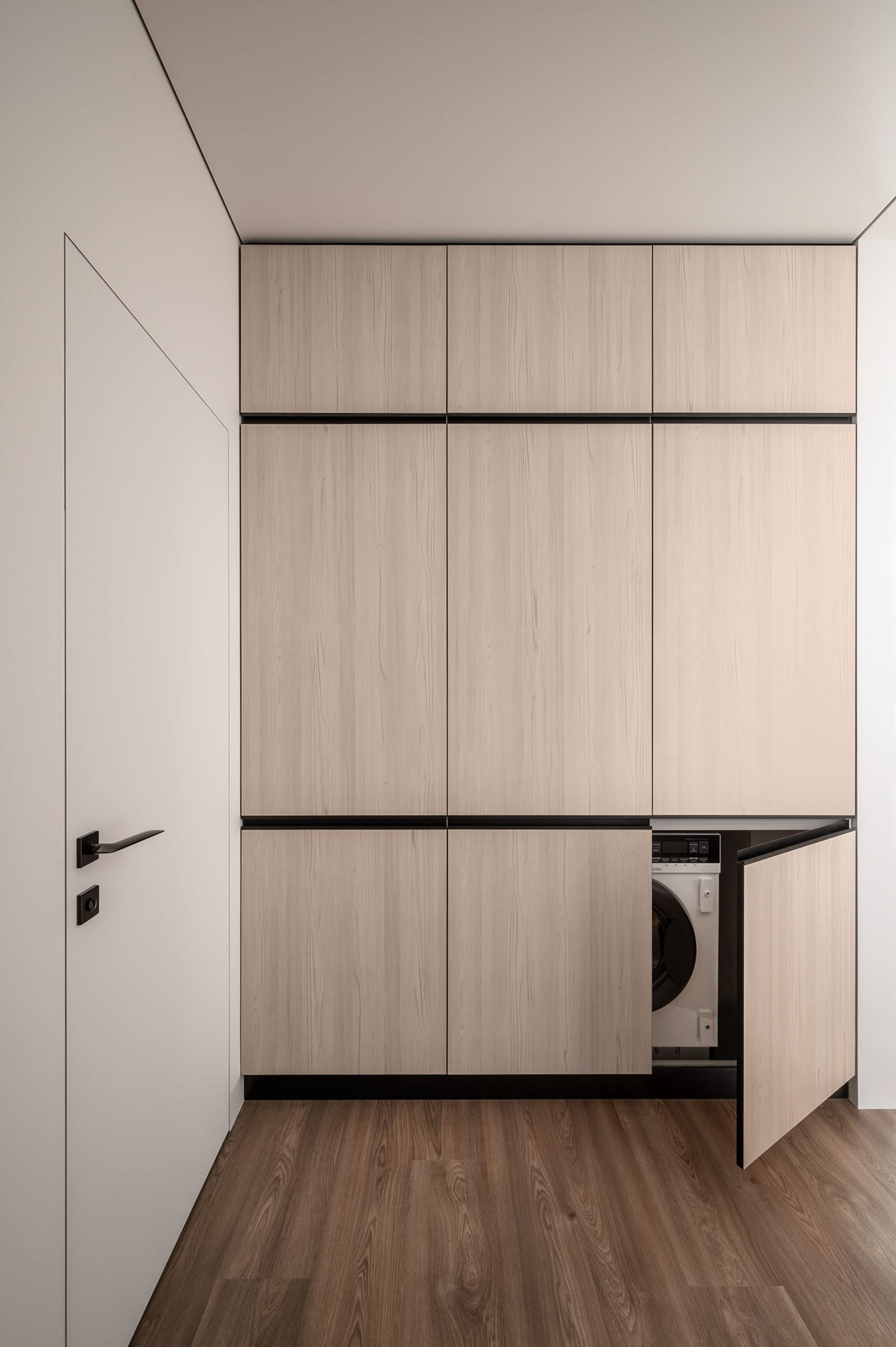 Modern laundry room featuring minimalist, wood-cabinet design for functional and stylish utility space.