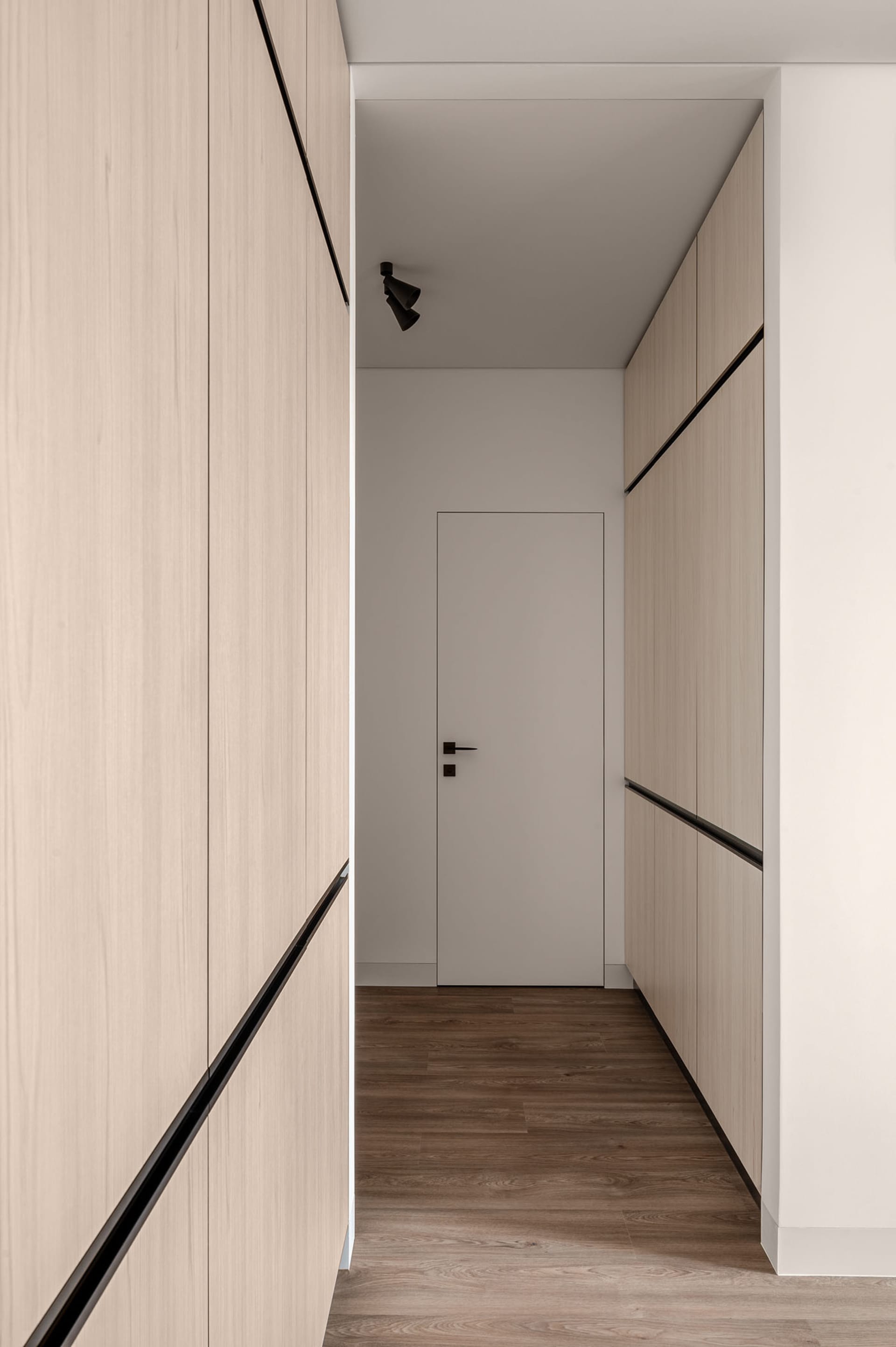 A modern, minimalist interior design corridor featuring wooden panels and sleek, linear accents.