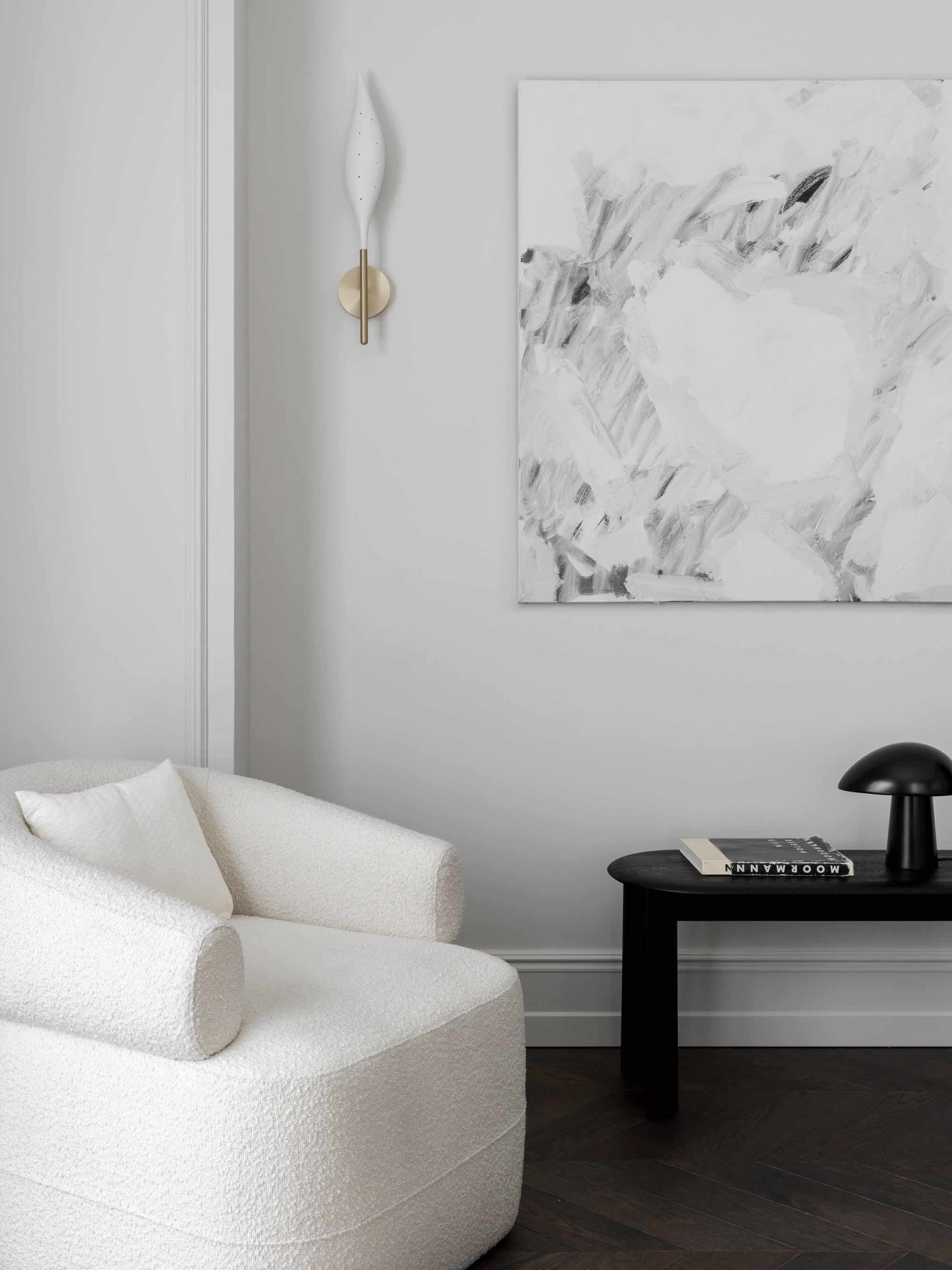 Minimalist living room featuring a textured plush armchair, abstract black and white artwork, black side table, and sleek bla