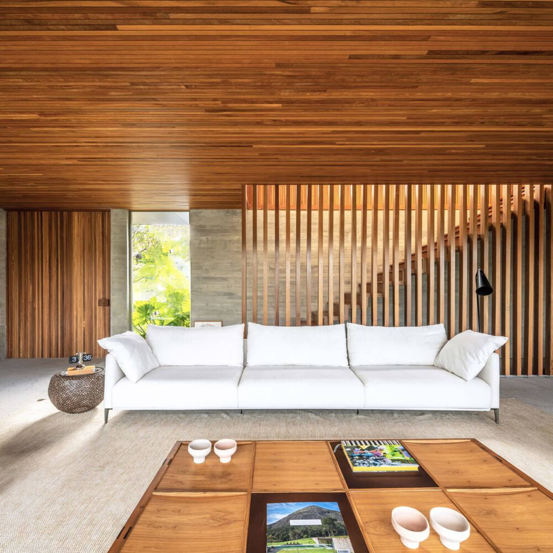 A minimalist living room with a white sofa, a wooden coffee table, and a wooden ceiling and walls