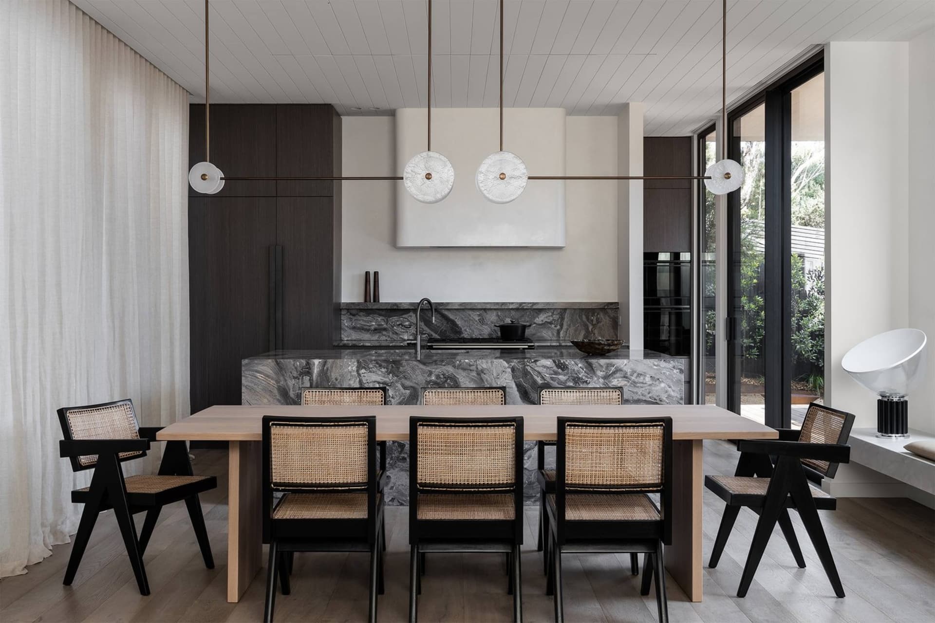 Modern residential kitchen featuring luxurious marble countertops and backsplash, with dark wooden cabinets and a sleek, mini