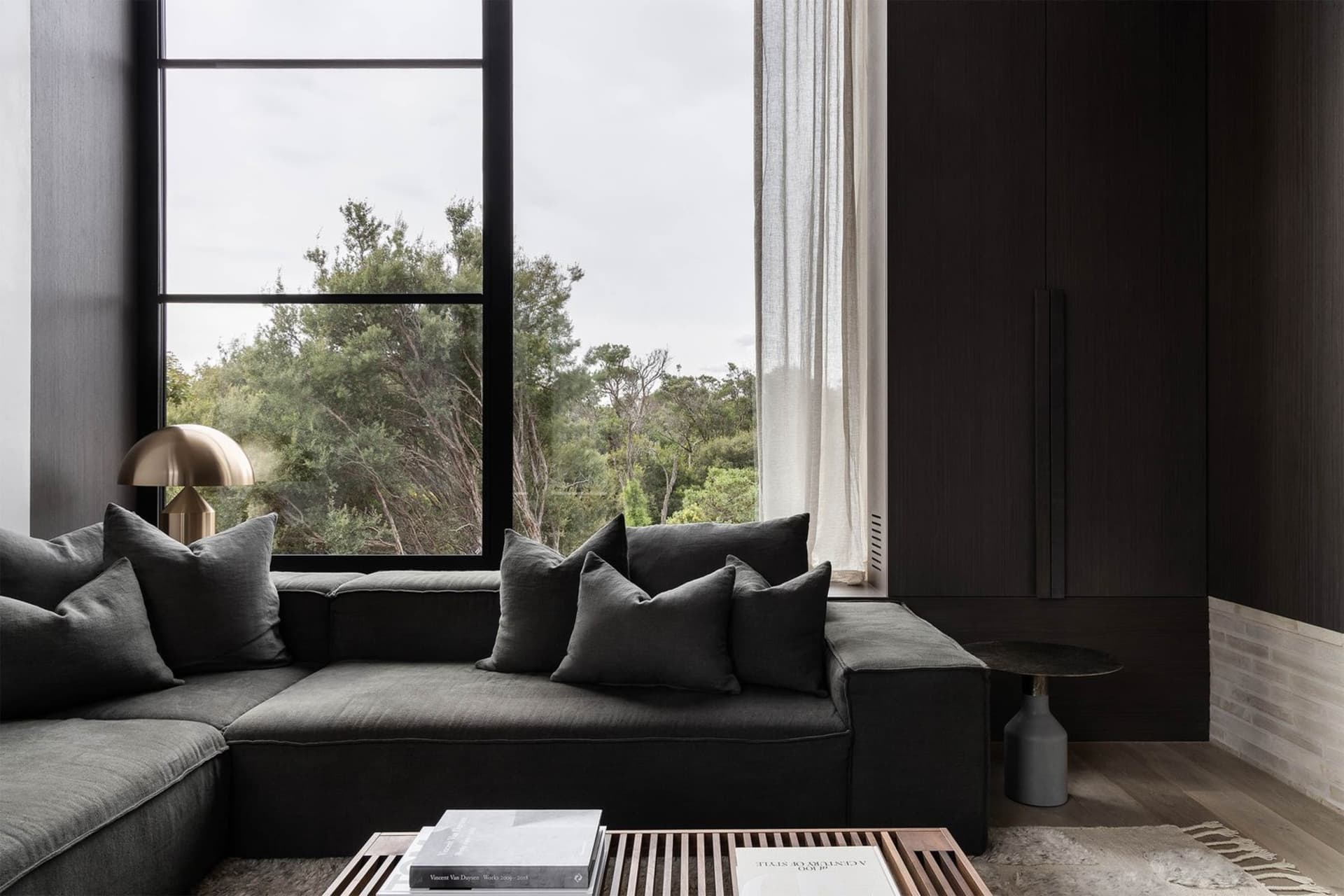 Modern living room featuring a black sofa with grey pillows.