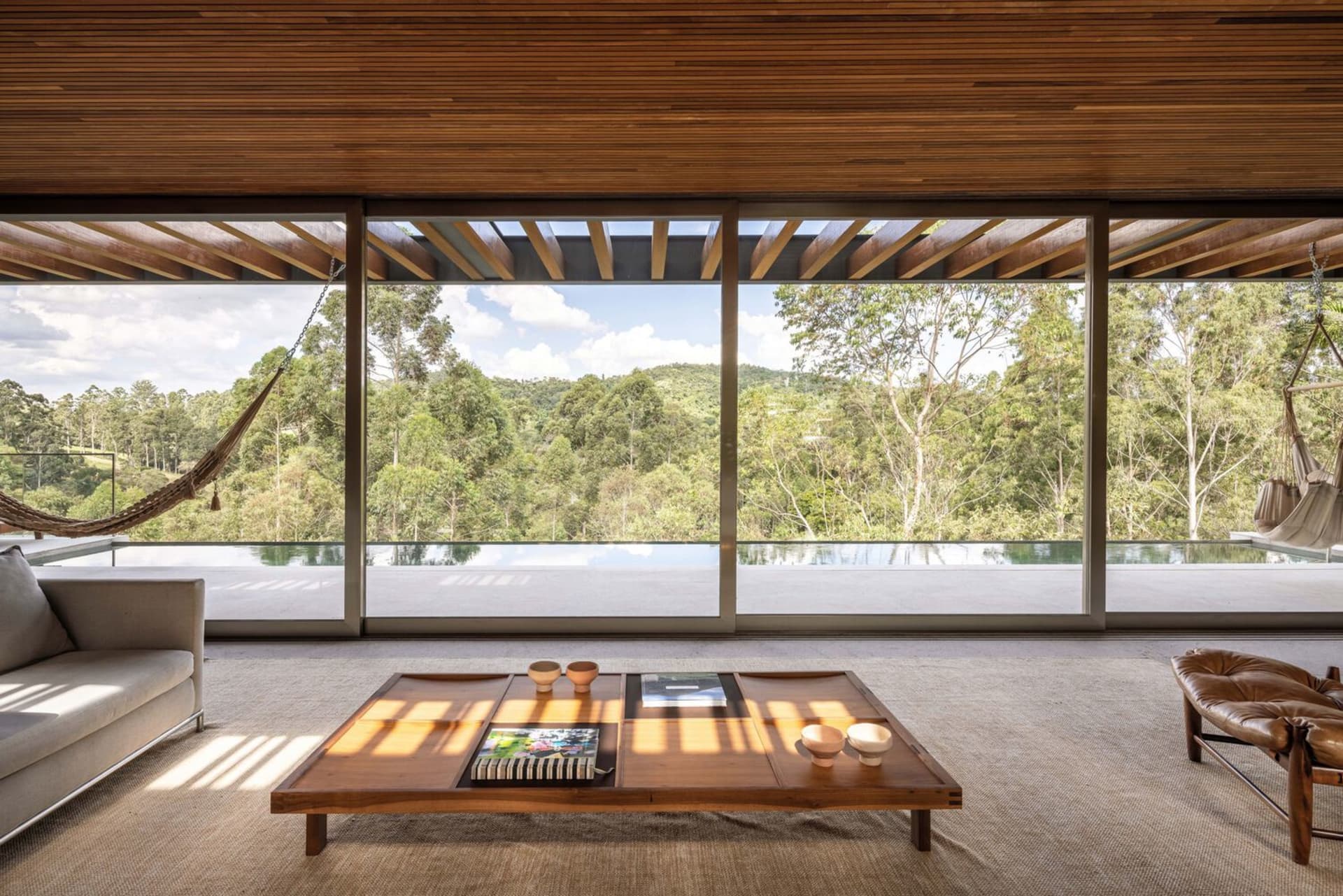 A modern living room featuring wooden furniture and glass elements.