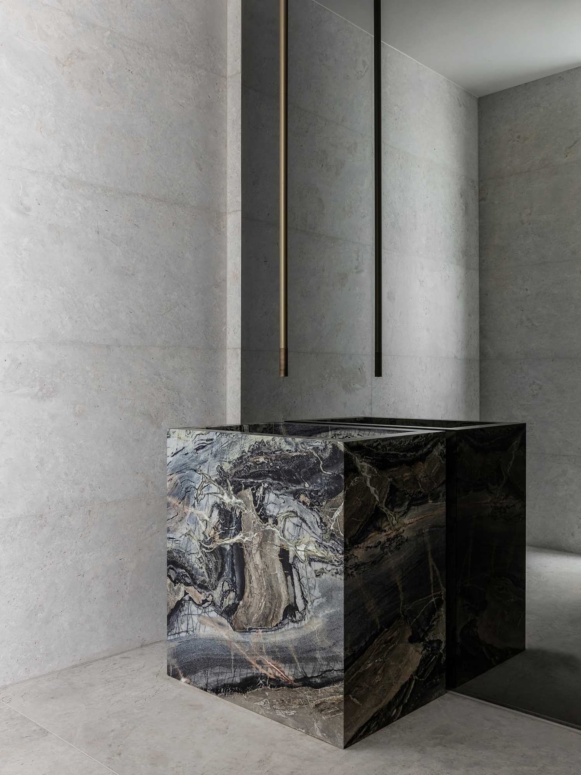 A modern, minimalist bathroom features sleek marble fixtures and a gray marble wall.