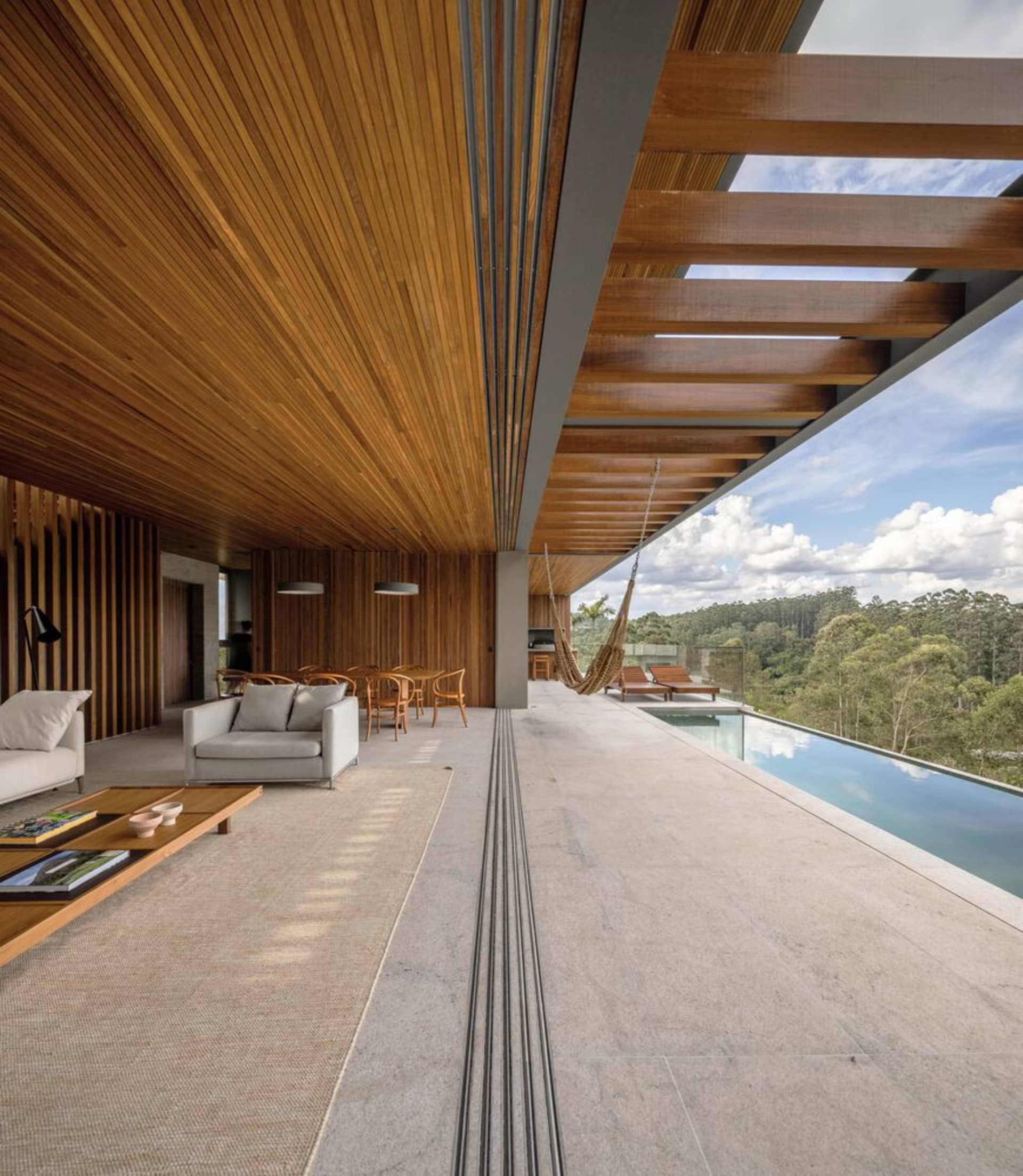 Modern, open-plan residential space featuring a concrete floor and large windows overlooking the natural landscape.