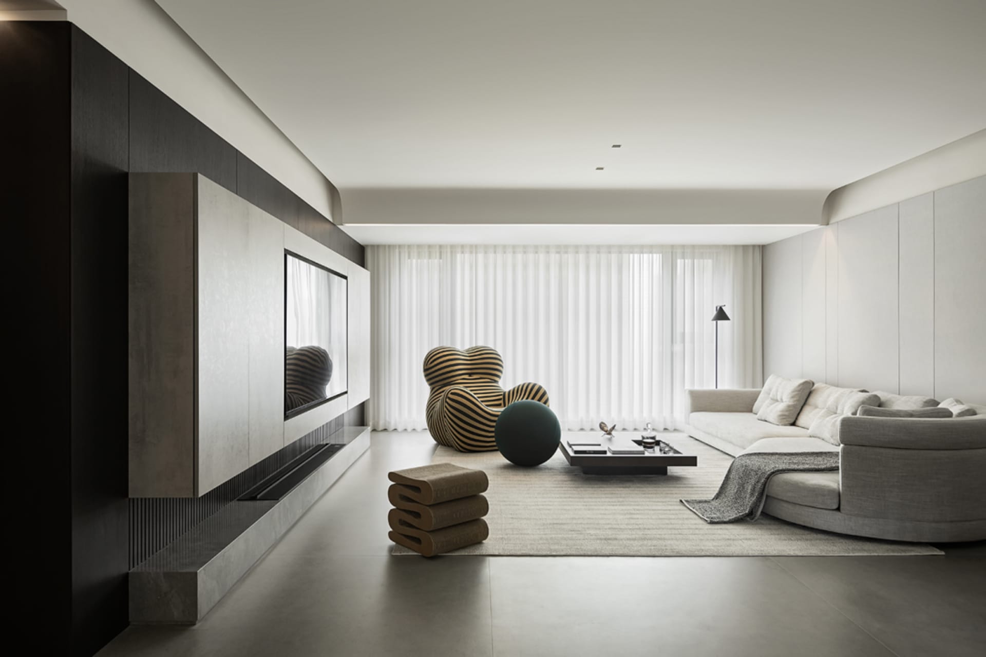 Modern minimalist living room featuring a contemporary sofa, armchair, and coffee table, with a sleek entertainment unit and
