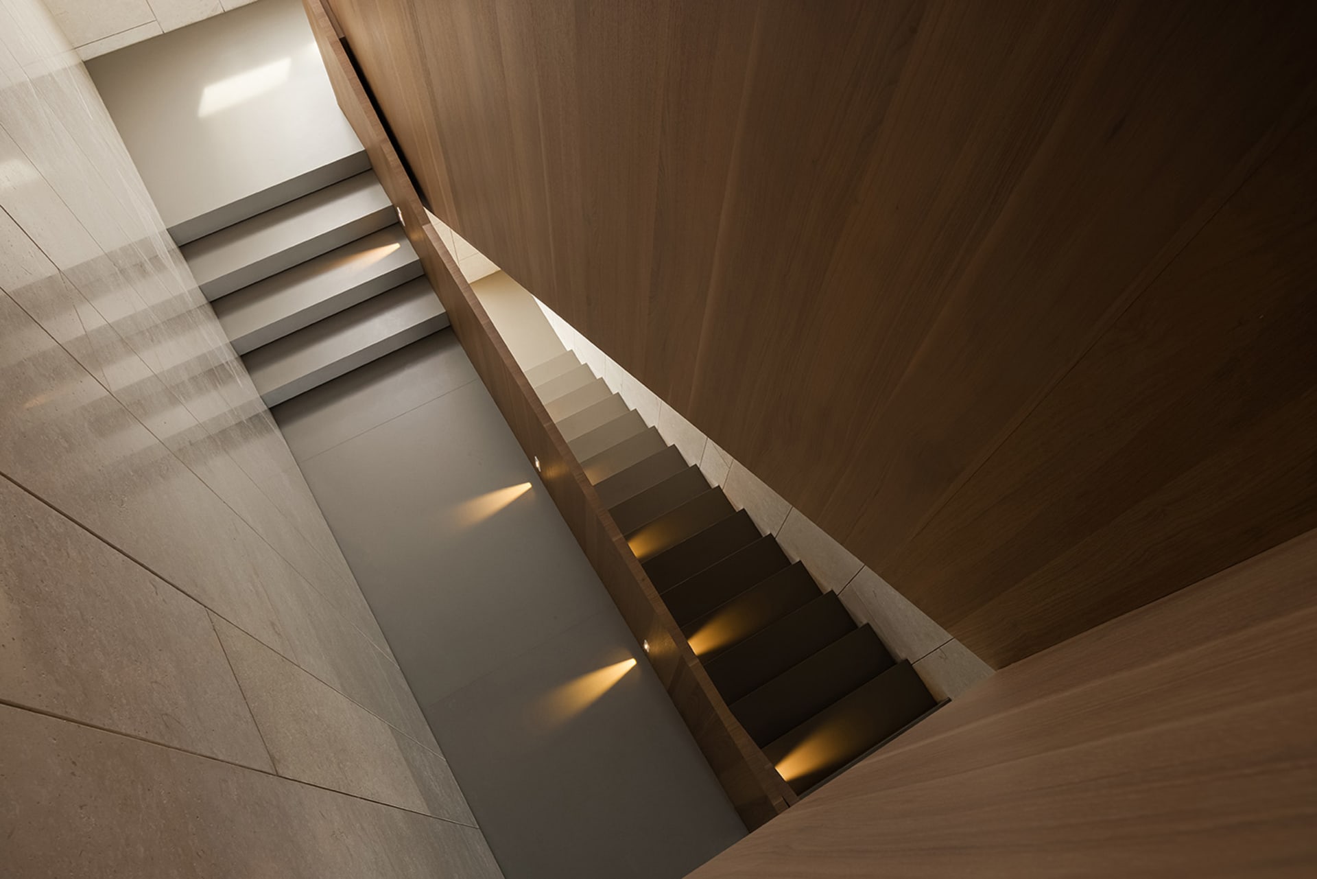 Modern minimalist staircase with wooden treads and illuminated steps, showcasing sleek and elegant design