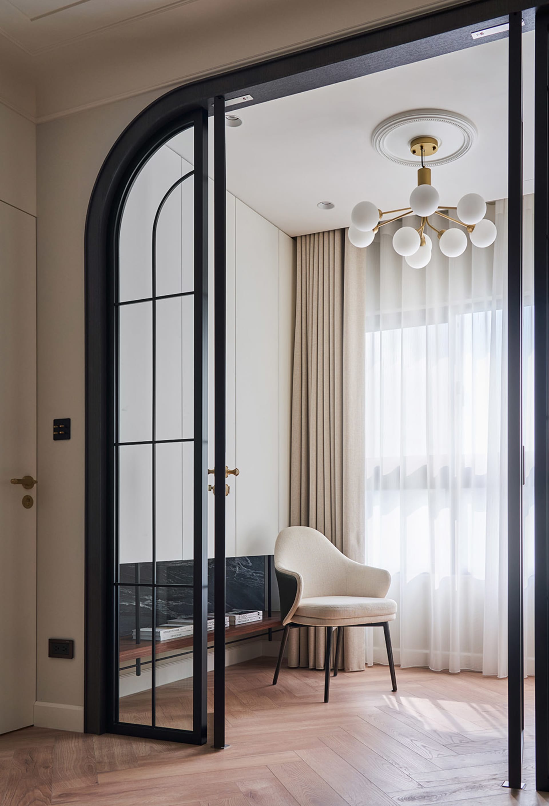 A modern living room with wood flooring, glass sliding doors, and curtains.