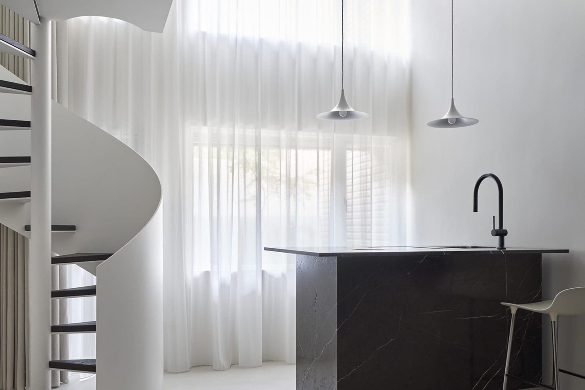Modern minimalist kitchen with marble countertop and pendant lights.