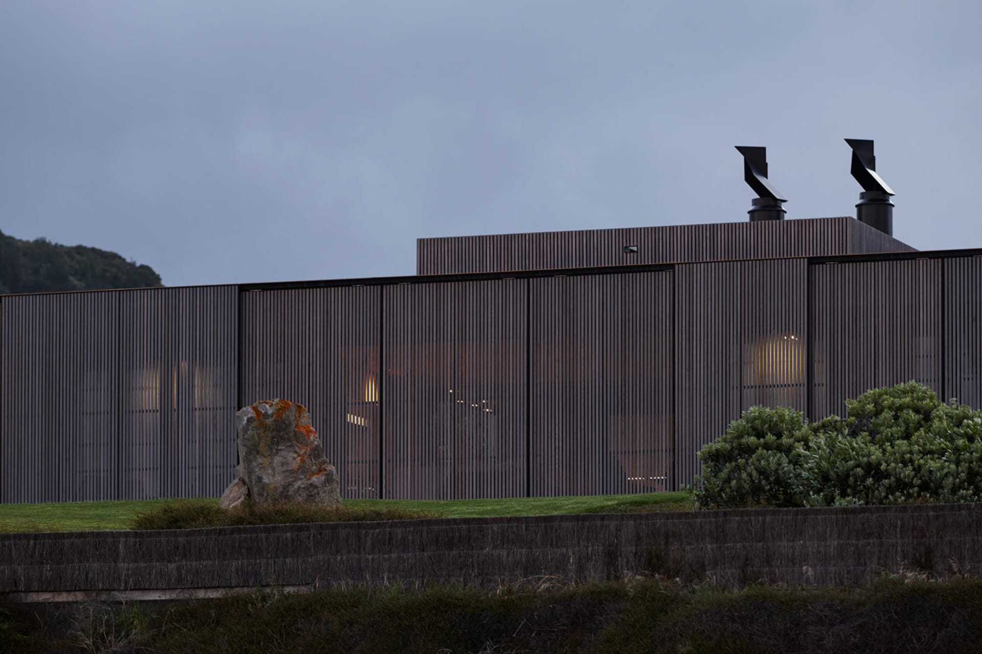 Modern residential exterior with metal cladding and illuminated windows.