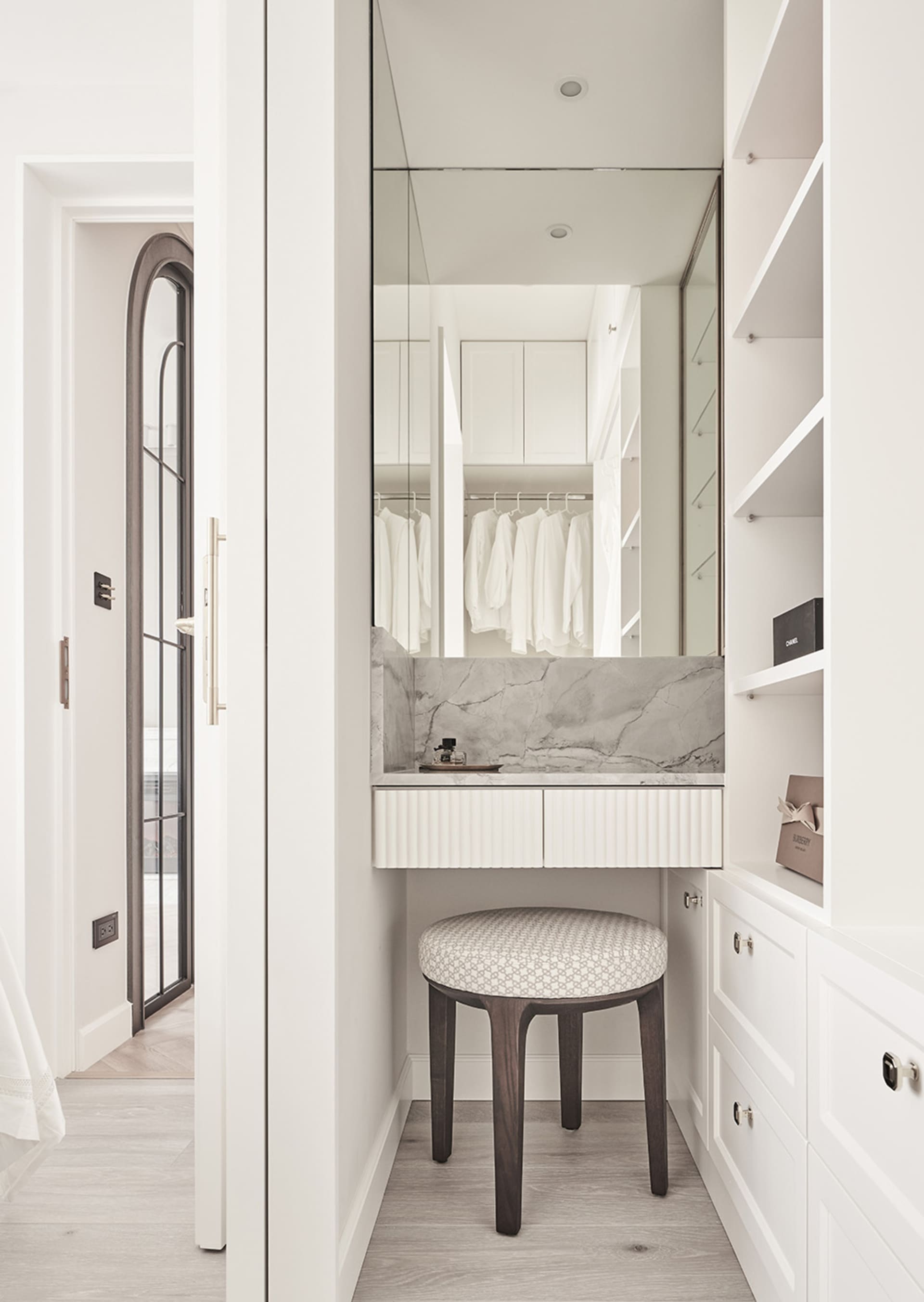 A modern closet with white marble counter and wooden stool