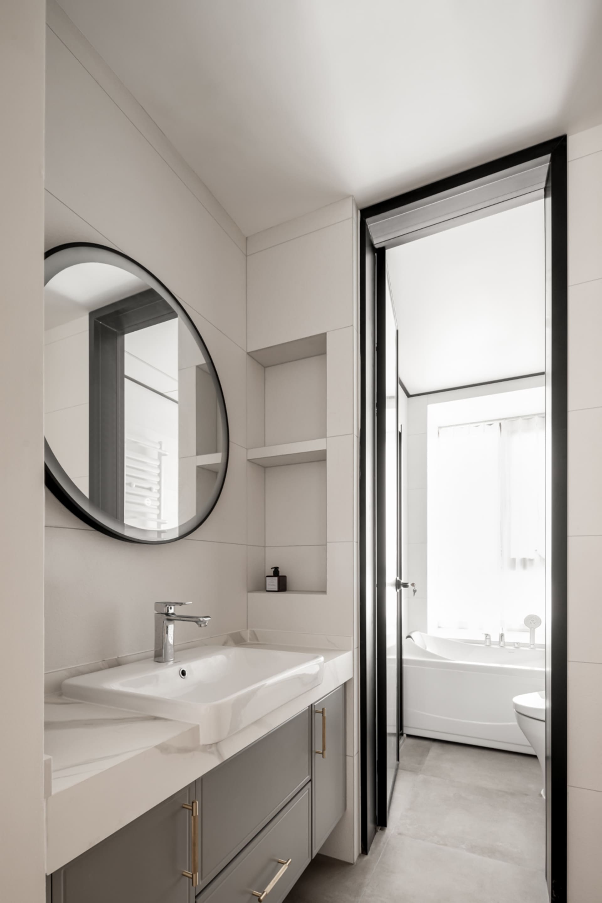 Modern, minimalist bathroom featuring sleek ceramic tiles, a floating vanity with a white countertop, and a mirror above the