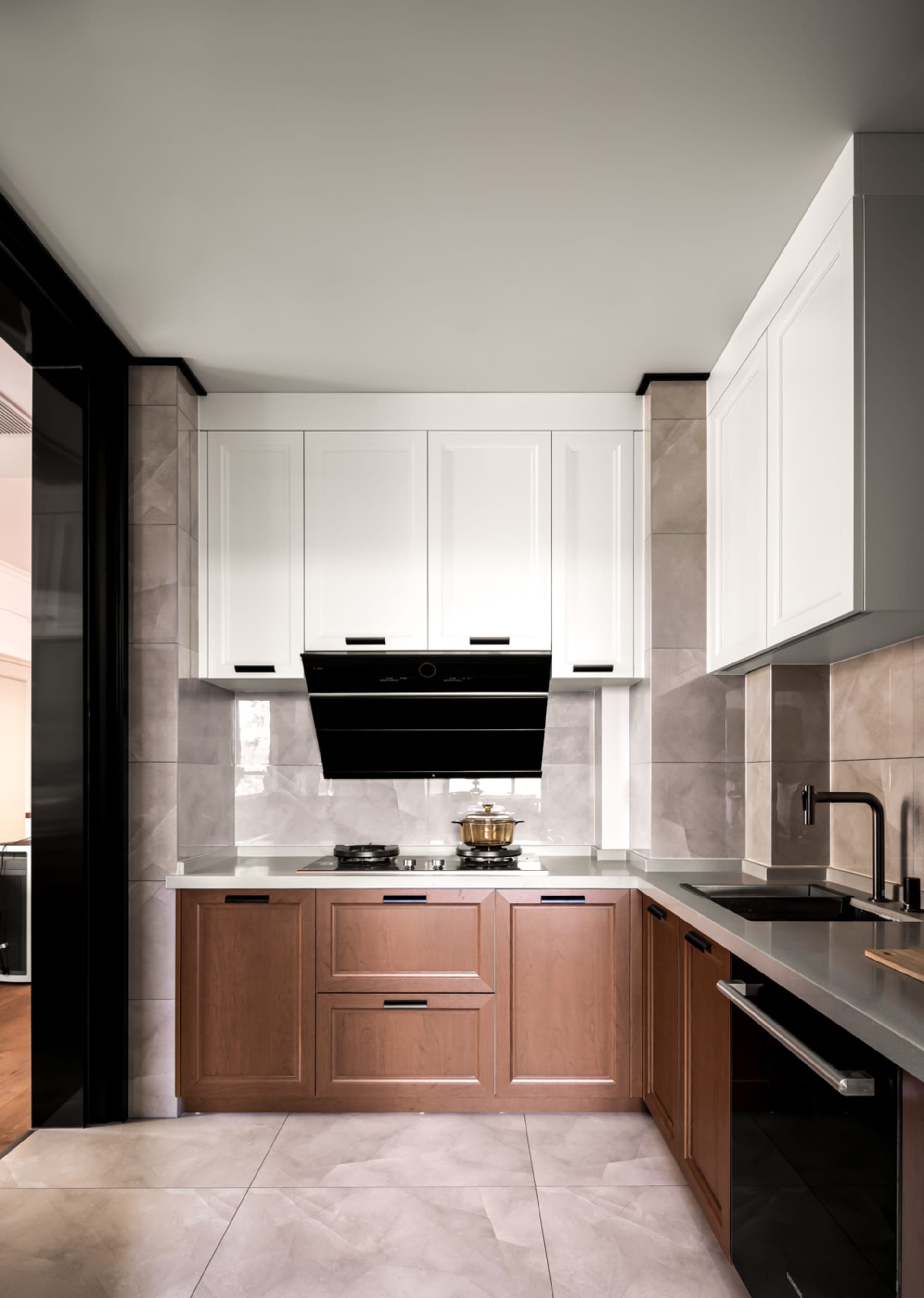 Modern kitchen with marble countertops, wooden cabinets, and a black stove.