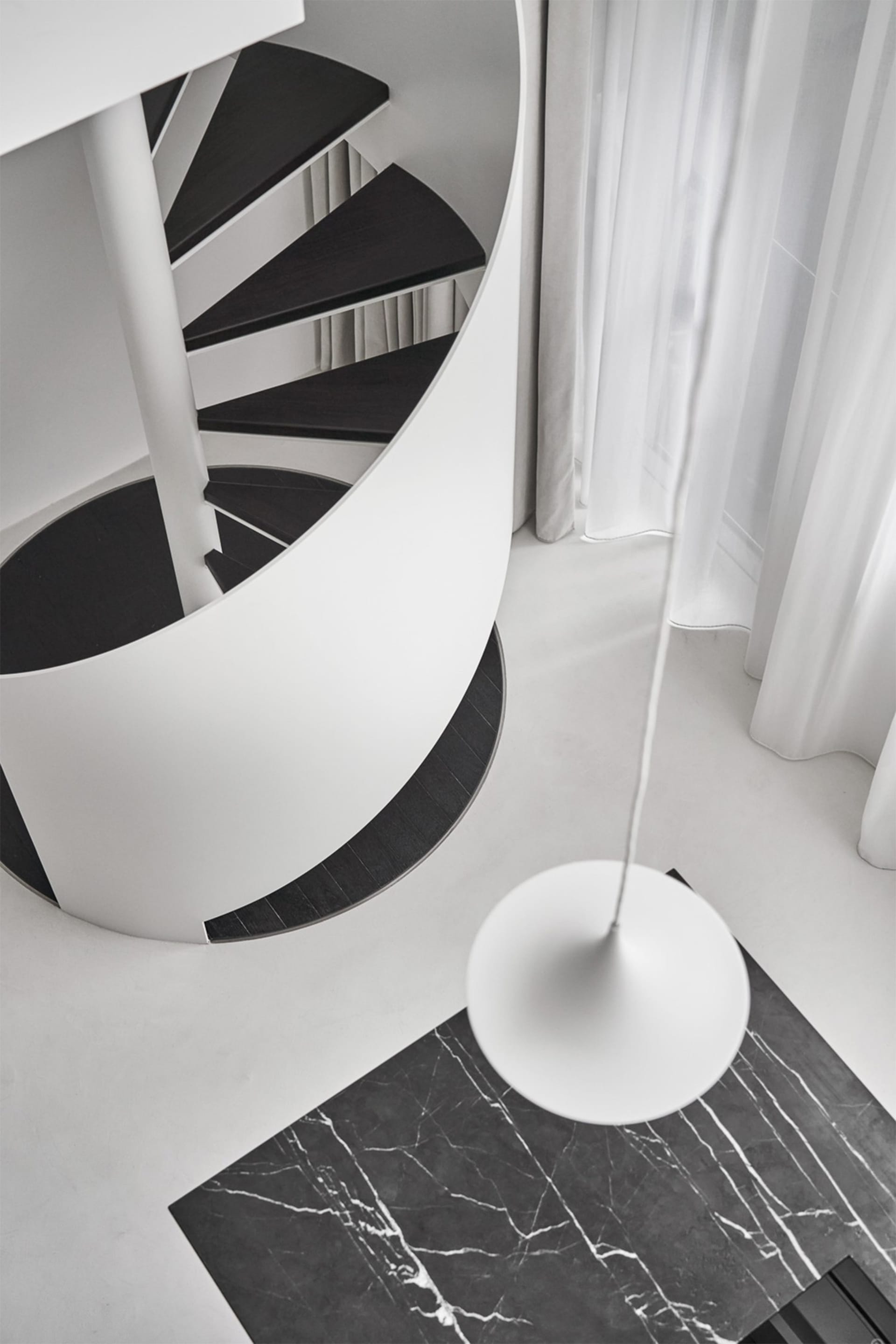 Minimalist design featuring a white concrete spiral staircase with a white floor lamp.