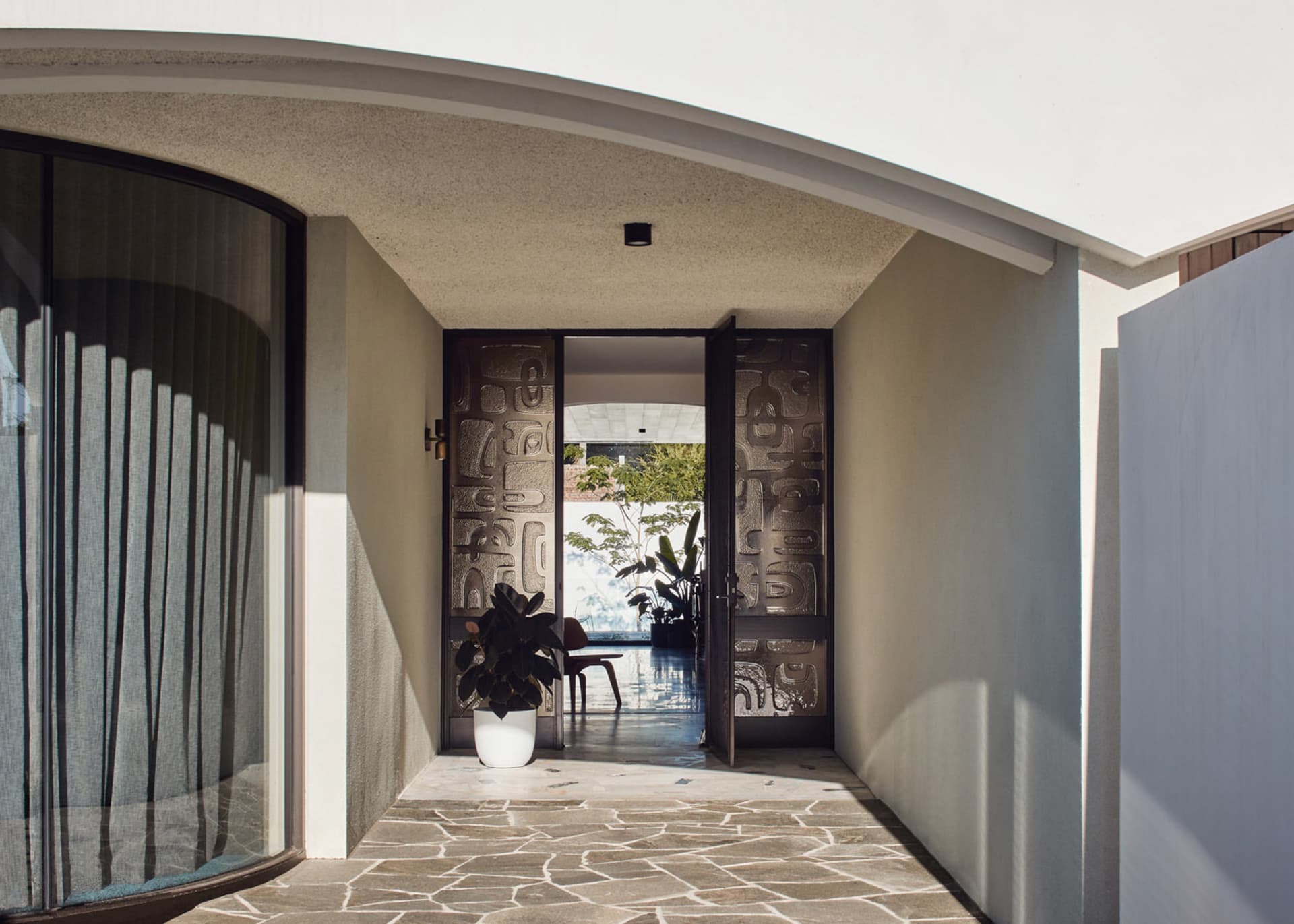 An open, modern entrance featuring a metal door and stone floor.