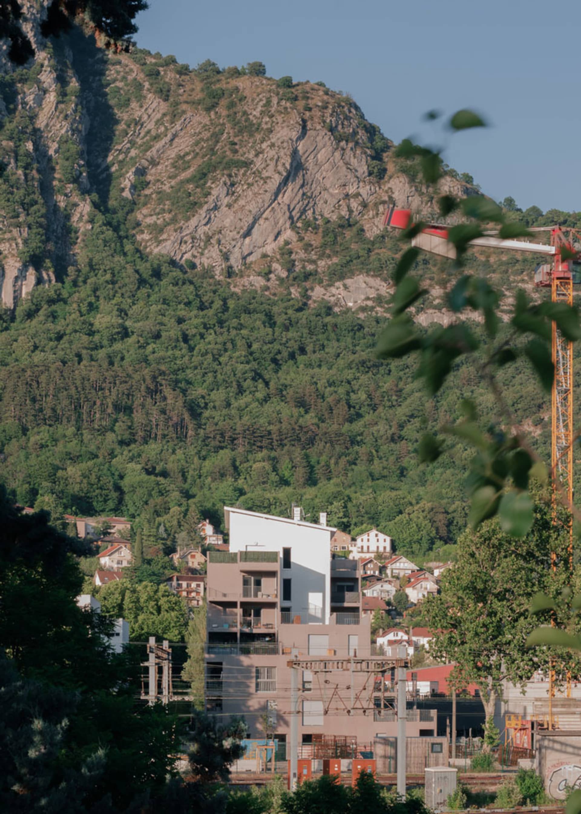 A view of buildings against a mountainous backdrop with lush greenery.