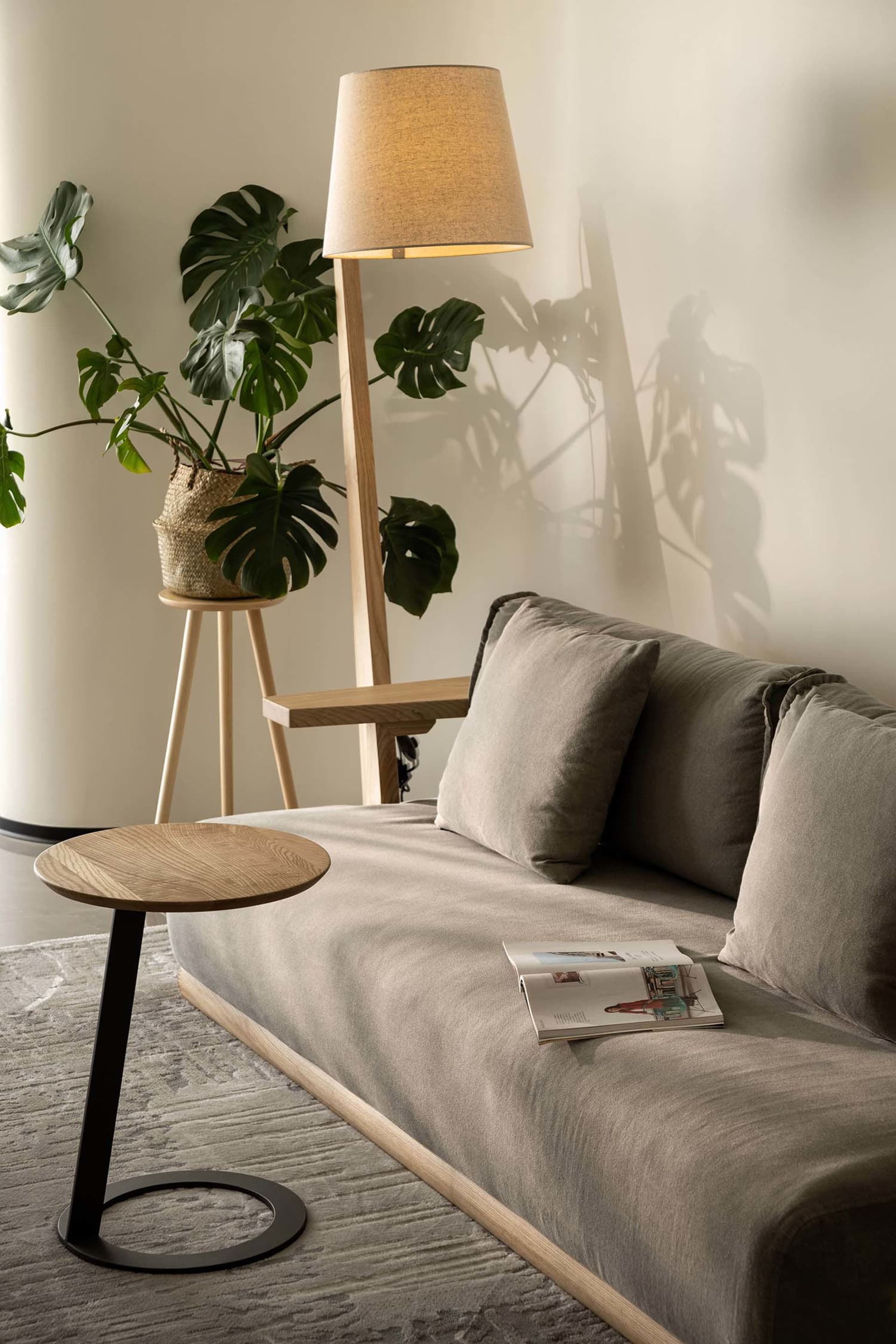 A minimalist living room featuring a couch, side table, lamp, and indoor plant.