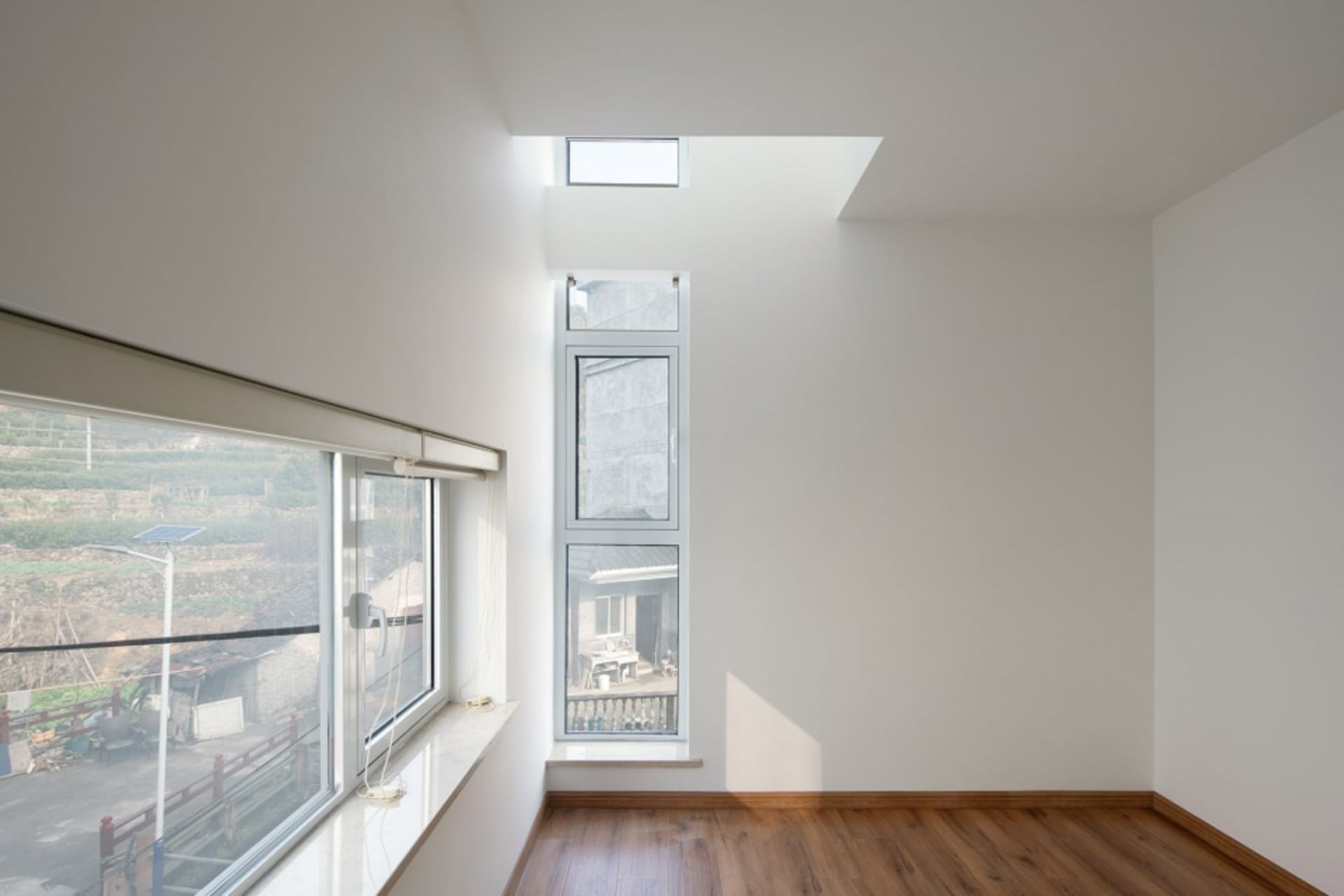 Minimalist white interior design with large windows and a skylight.