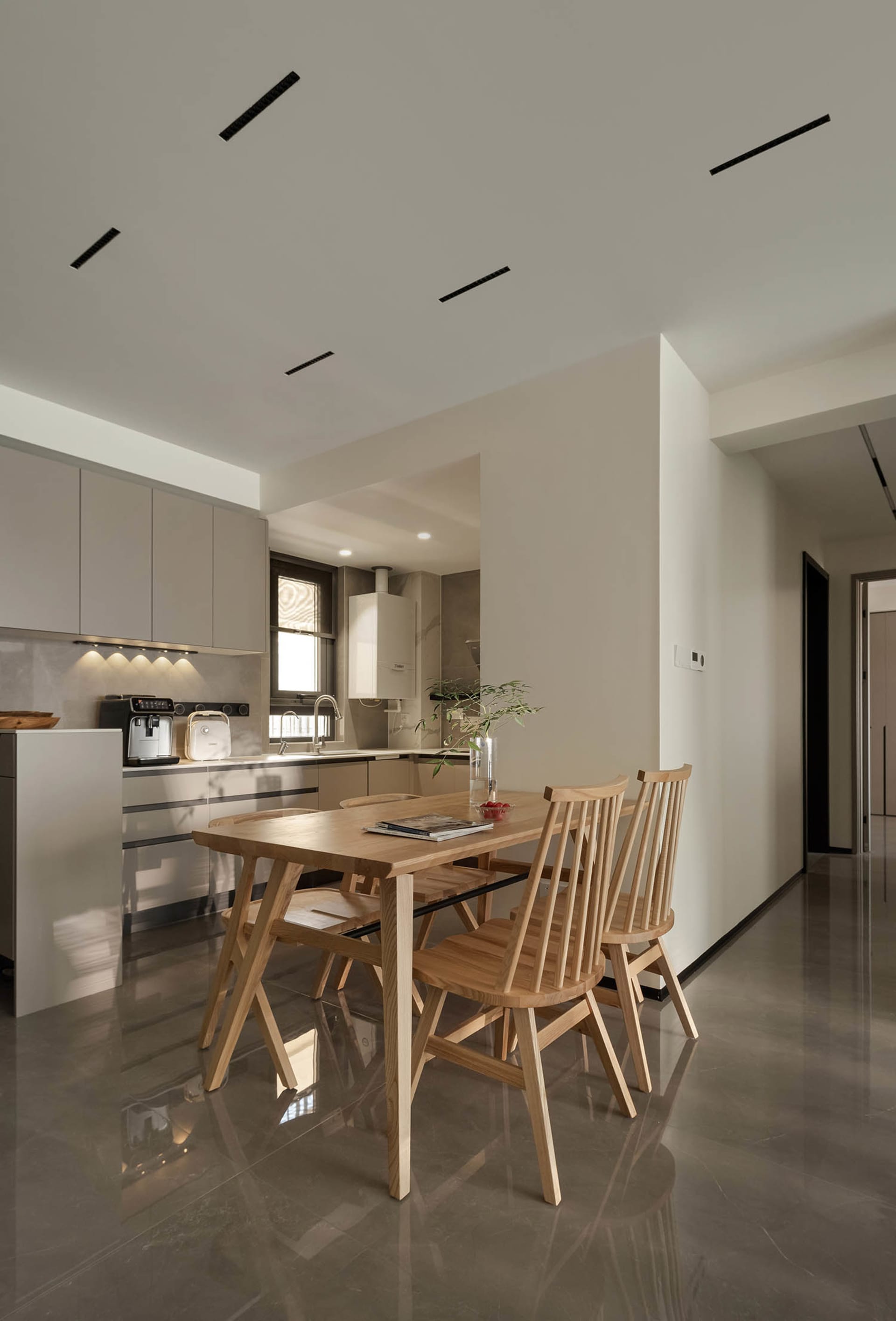 Modern kitchen with wooden table, marble countertops, and stainless steel appliances.