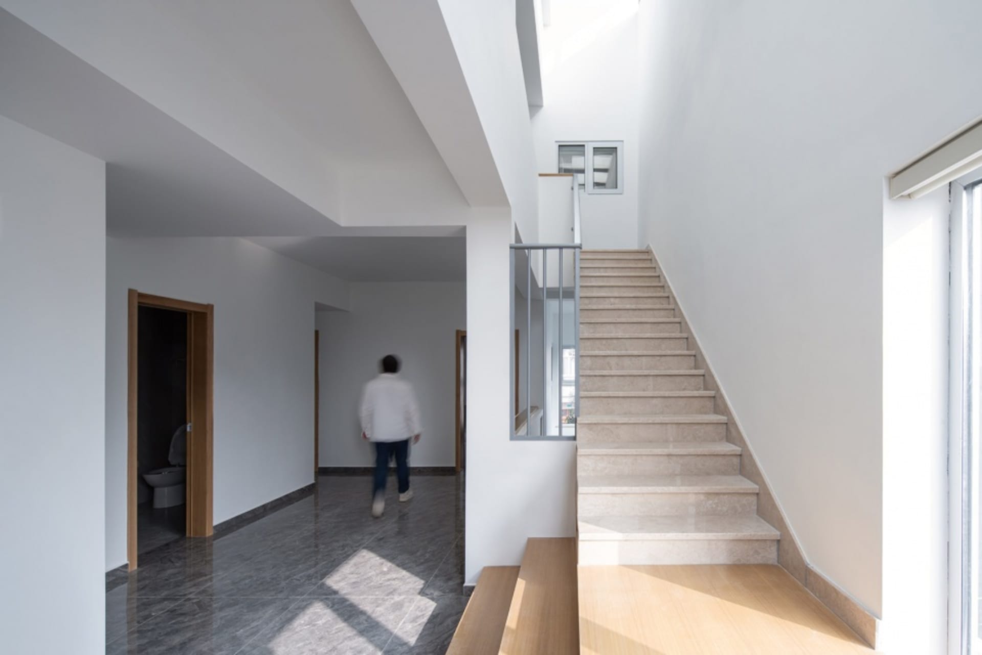 Modern stairway with marble steps surrounded by white walls and hardwood floors.