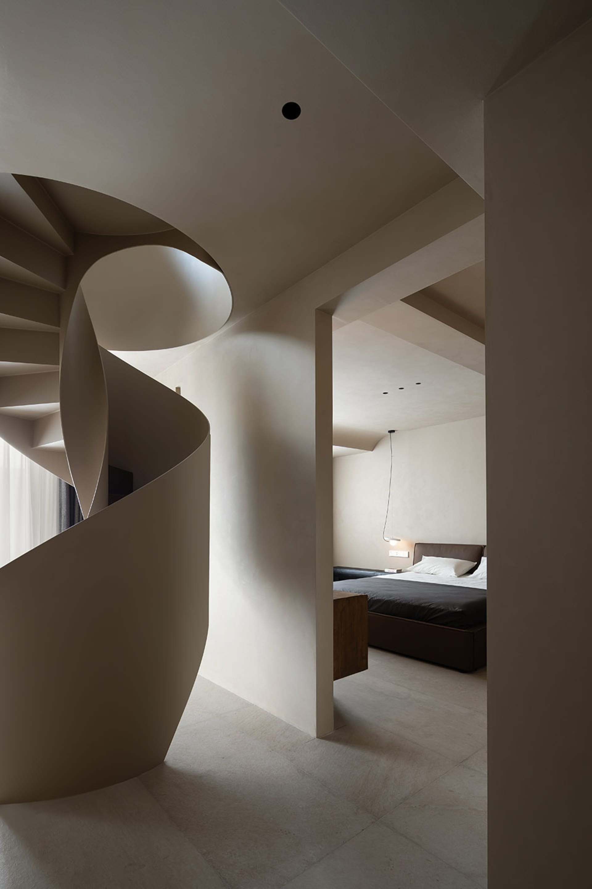 Modern residential interior featuring a spiral staircase made of concrete and wooden walls.