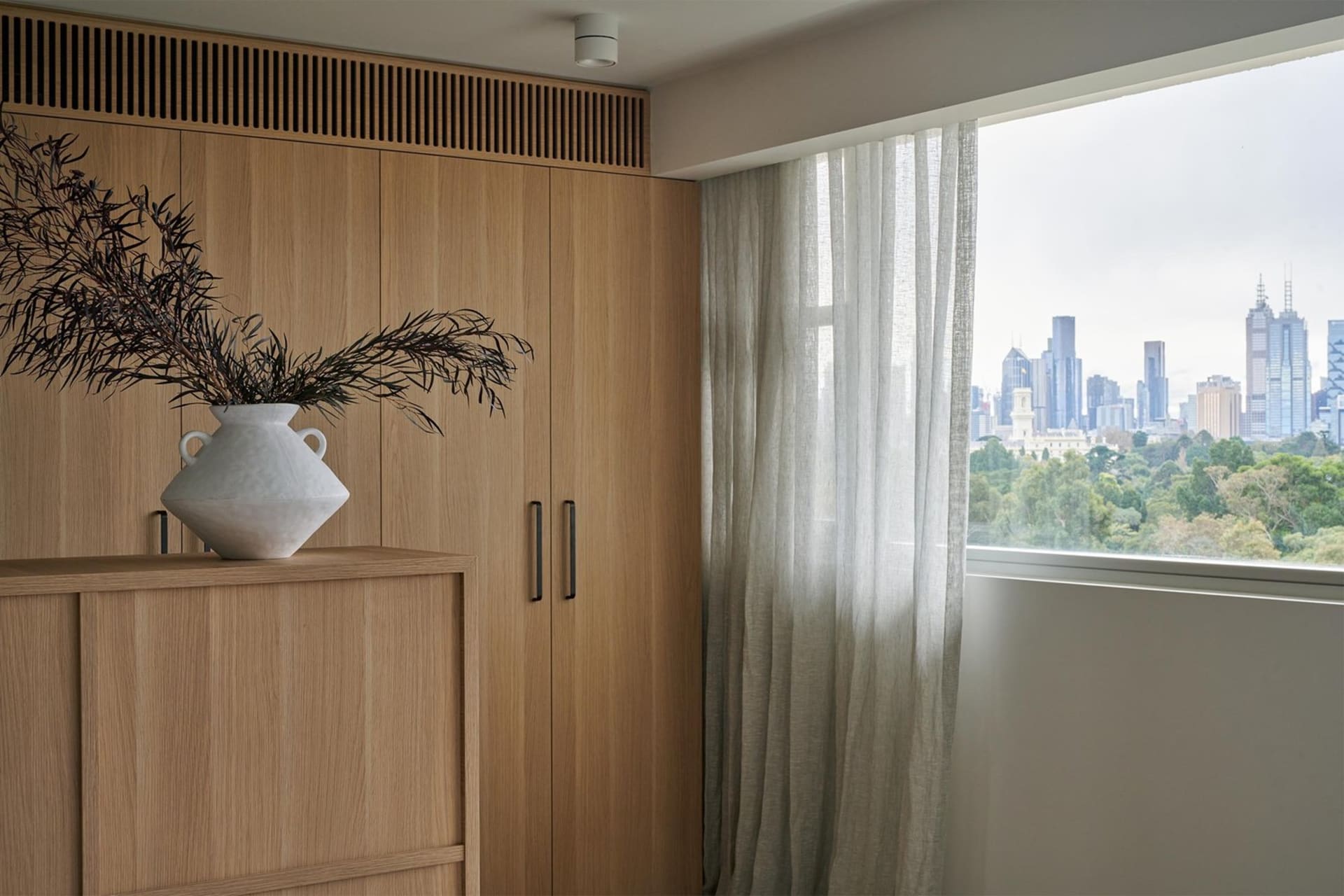 A modern residential interior featuring wooden cabinets and glass curtains.