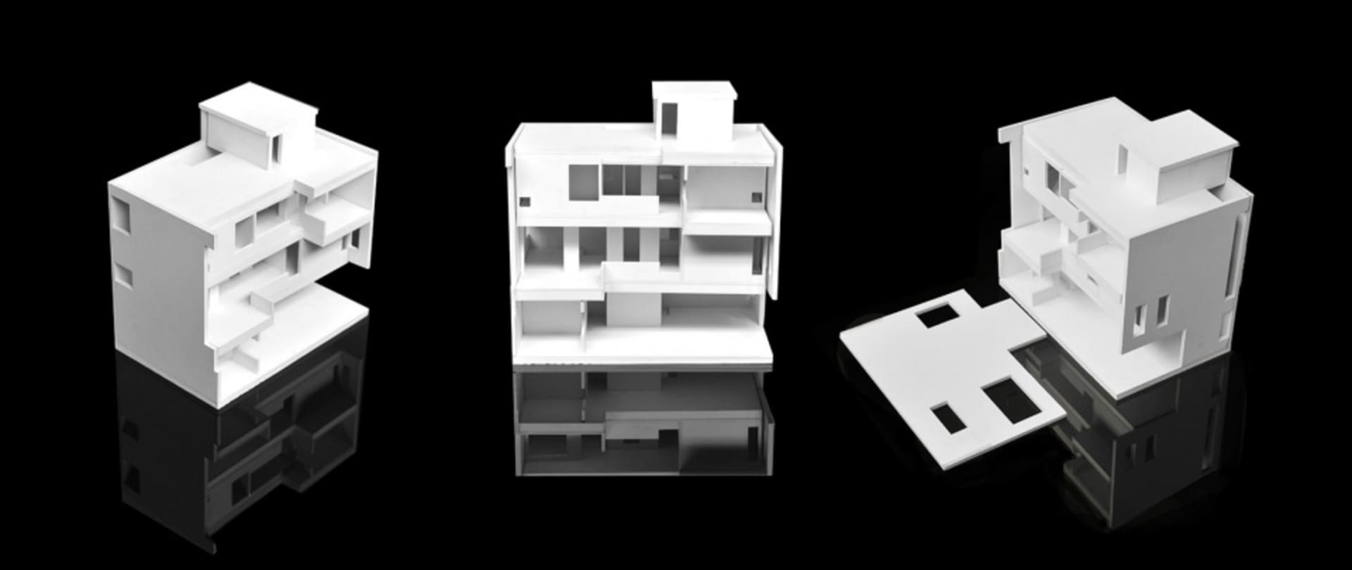 白色模組化建築結構紙模型，置於黑色反光表面上。