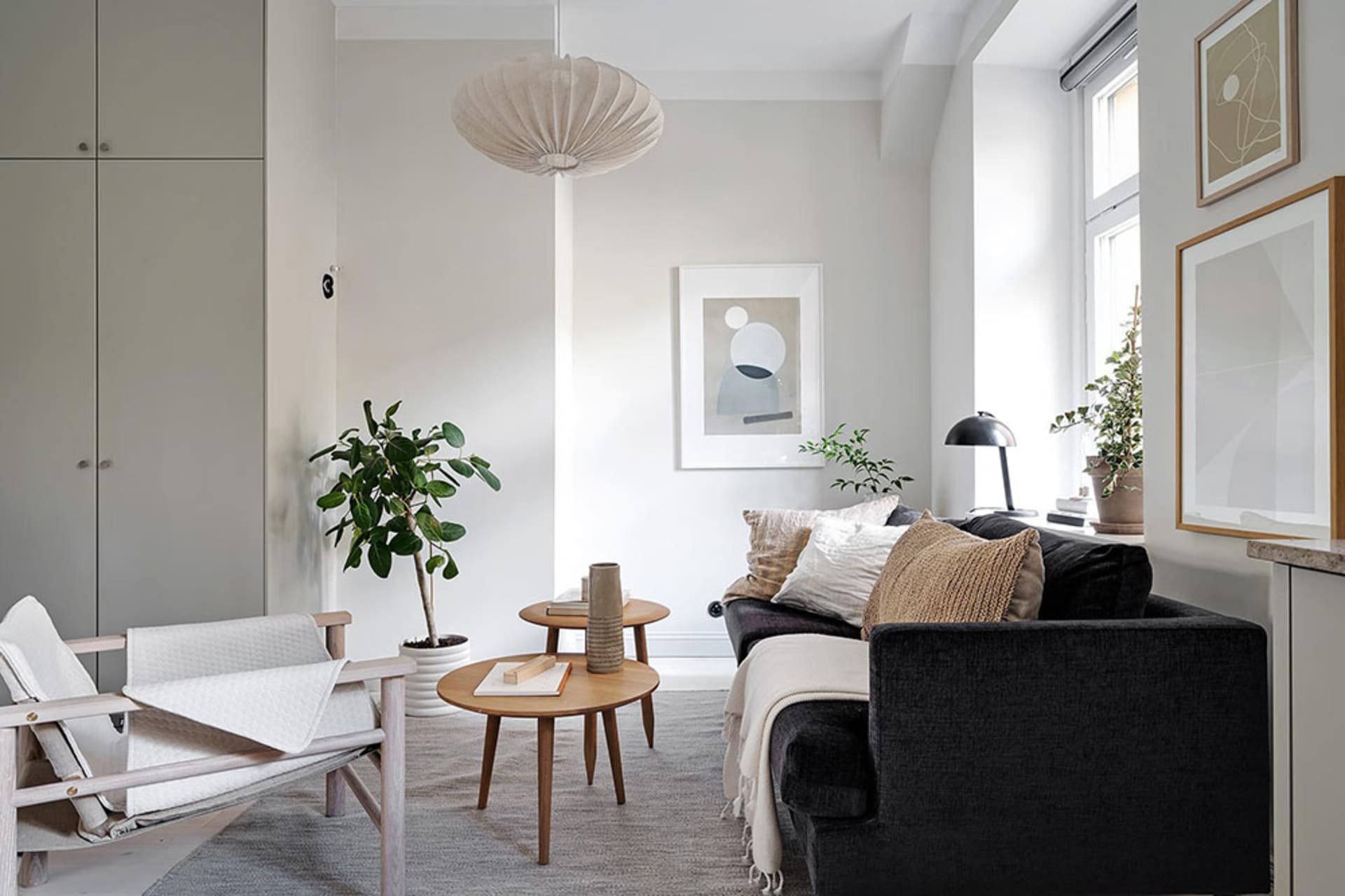 A minimalist living room with concrete floor, wooden furniture, and fabric cushions.