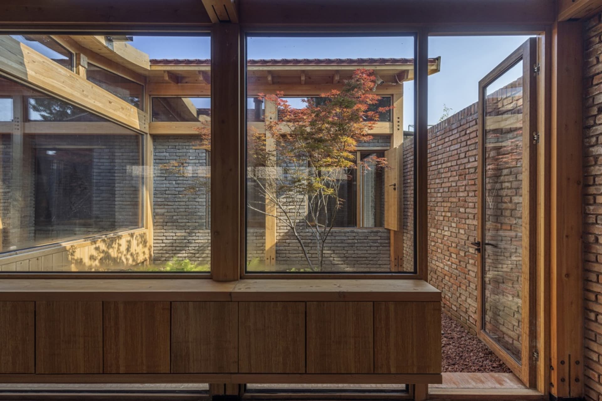 Modern living space with wooden walls, brick floors, and glass windows.