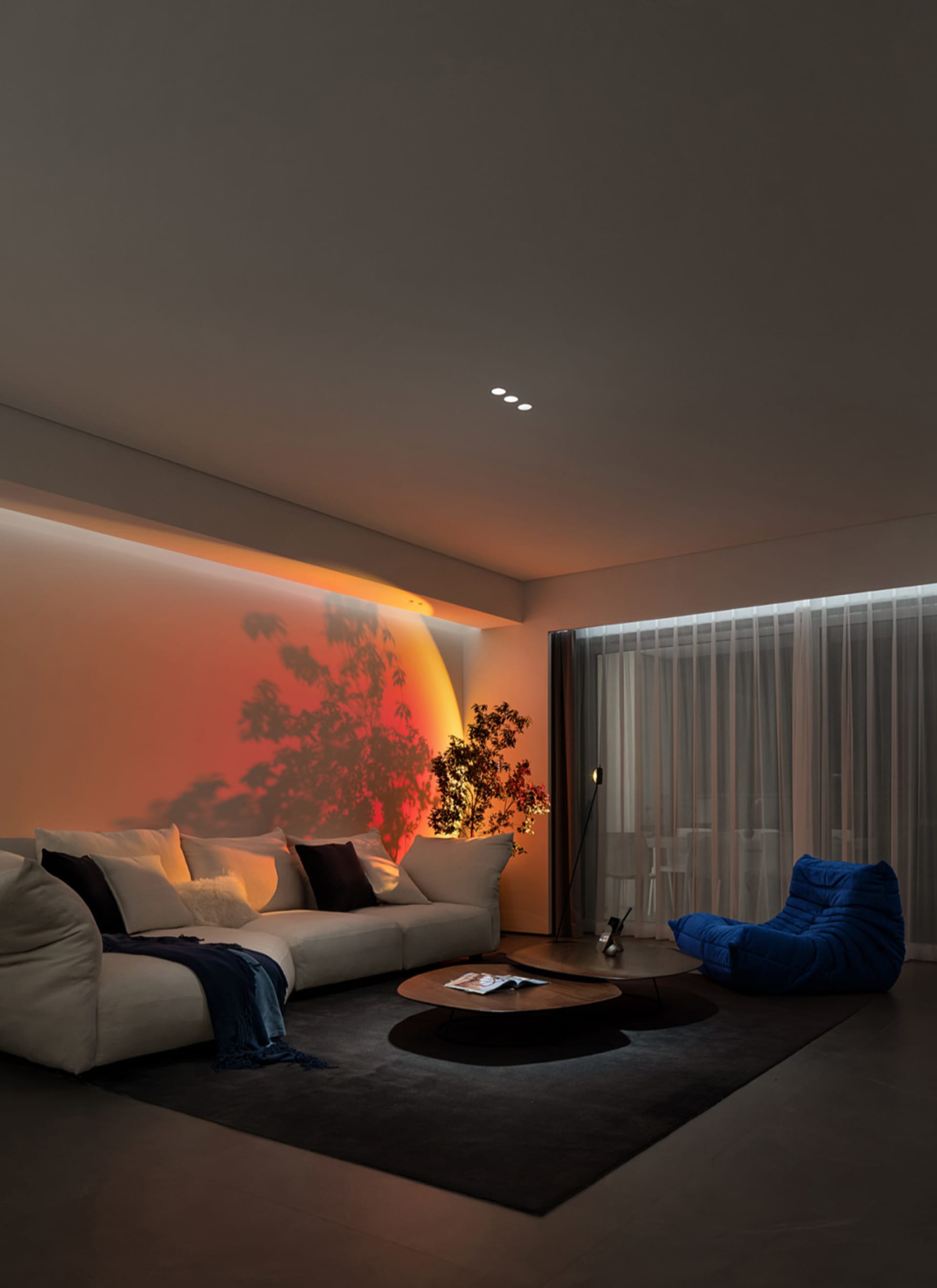 Modern living room featuring a comfortable fabric sofa, round wooden coffee tables, and blue bean bag chair against a white w