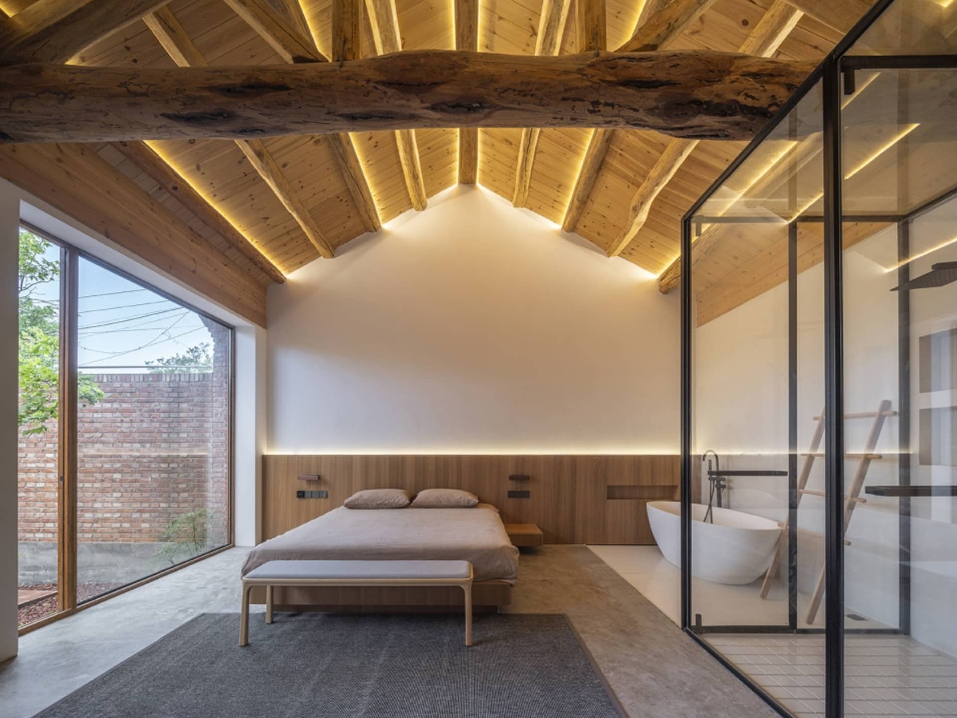 Modern minimalist bedroom featuring wooden elements and a white bathtub.