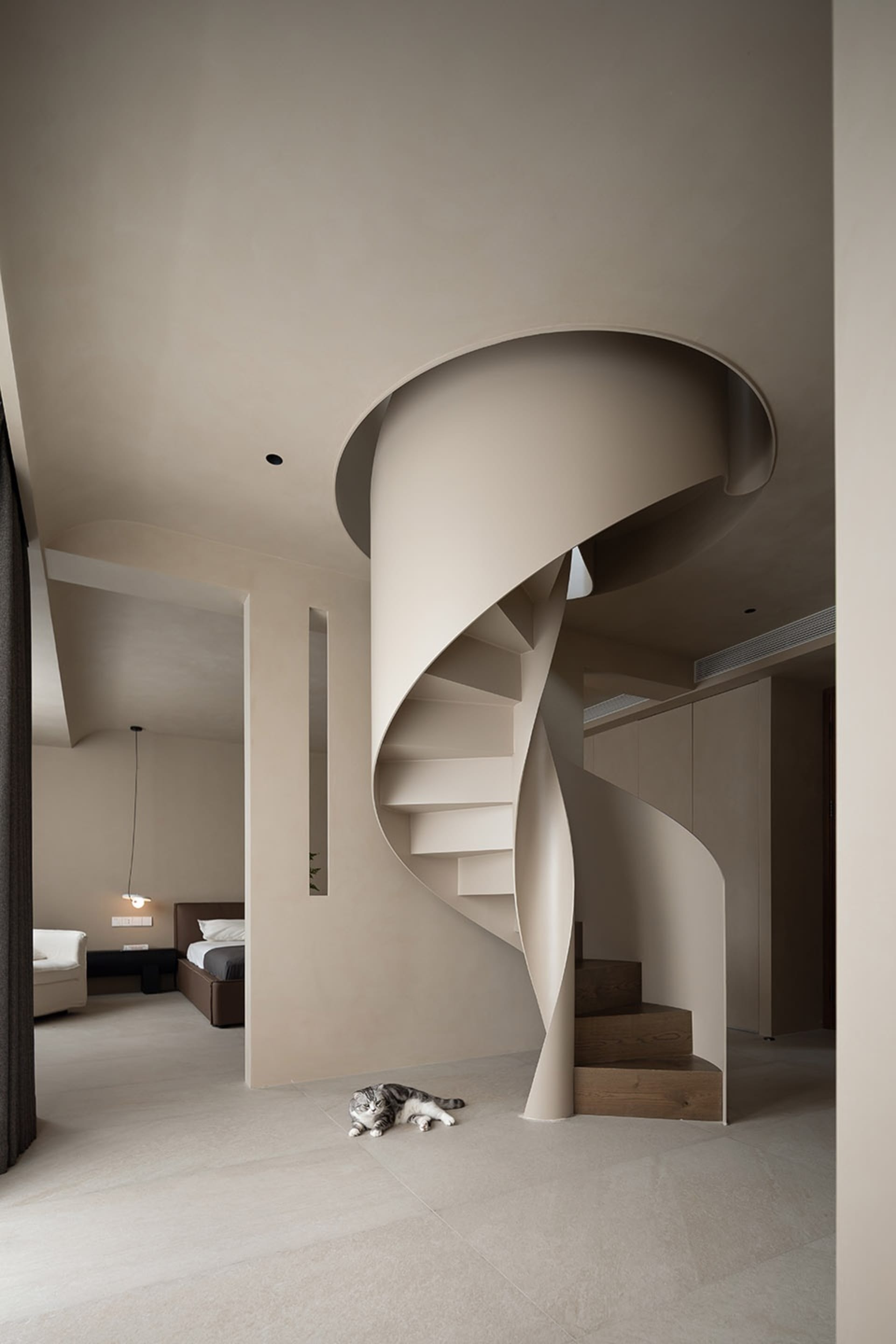 A minimalist, modern residential interior featuring a spiral staircase with light wood steps and a sleek, clean design.
