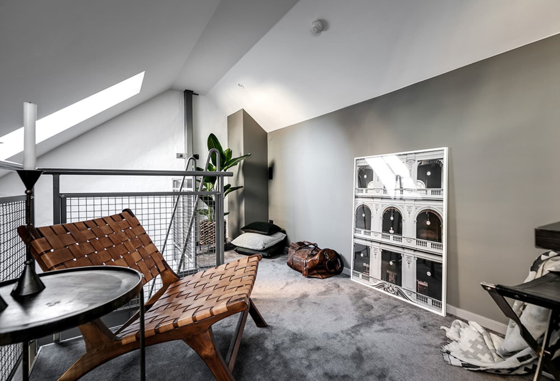A minimalist living space with wooden furniture and a large framed architectural print on the wall.