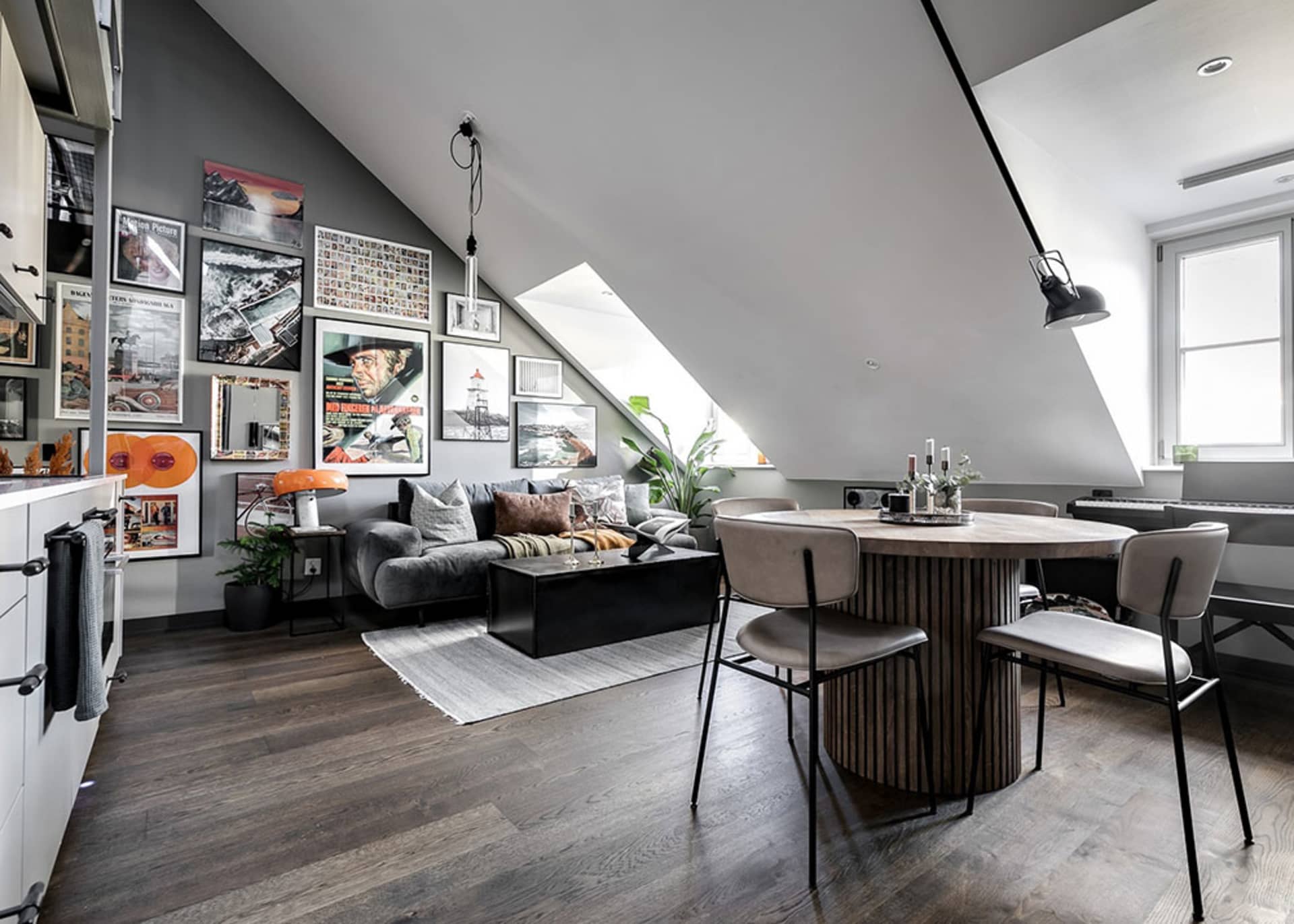Modern, spacious living room with a dark wood floor, grey sofa, and a circular dining table with upholstered chairs.