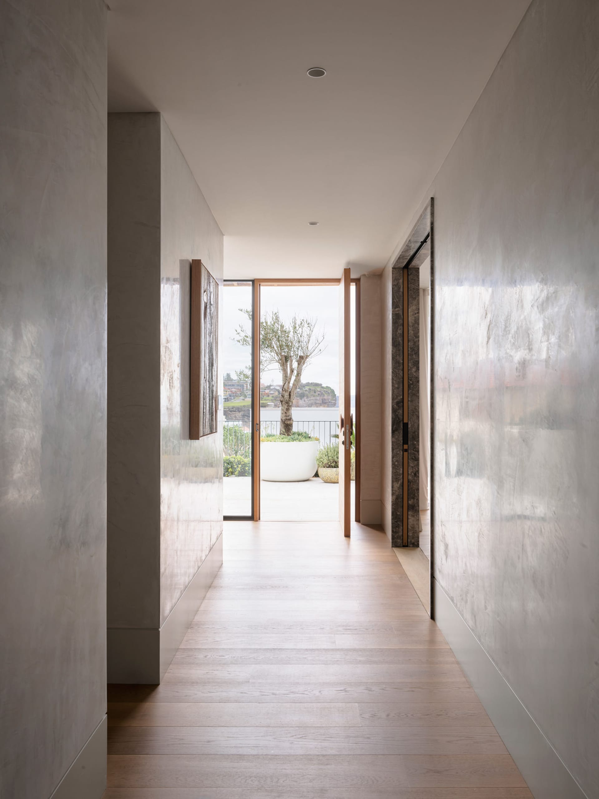 A modern marble hallway with a view leading to an outdoor patio area.
