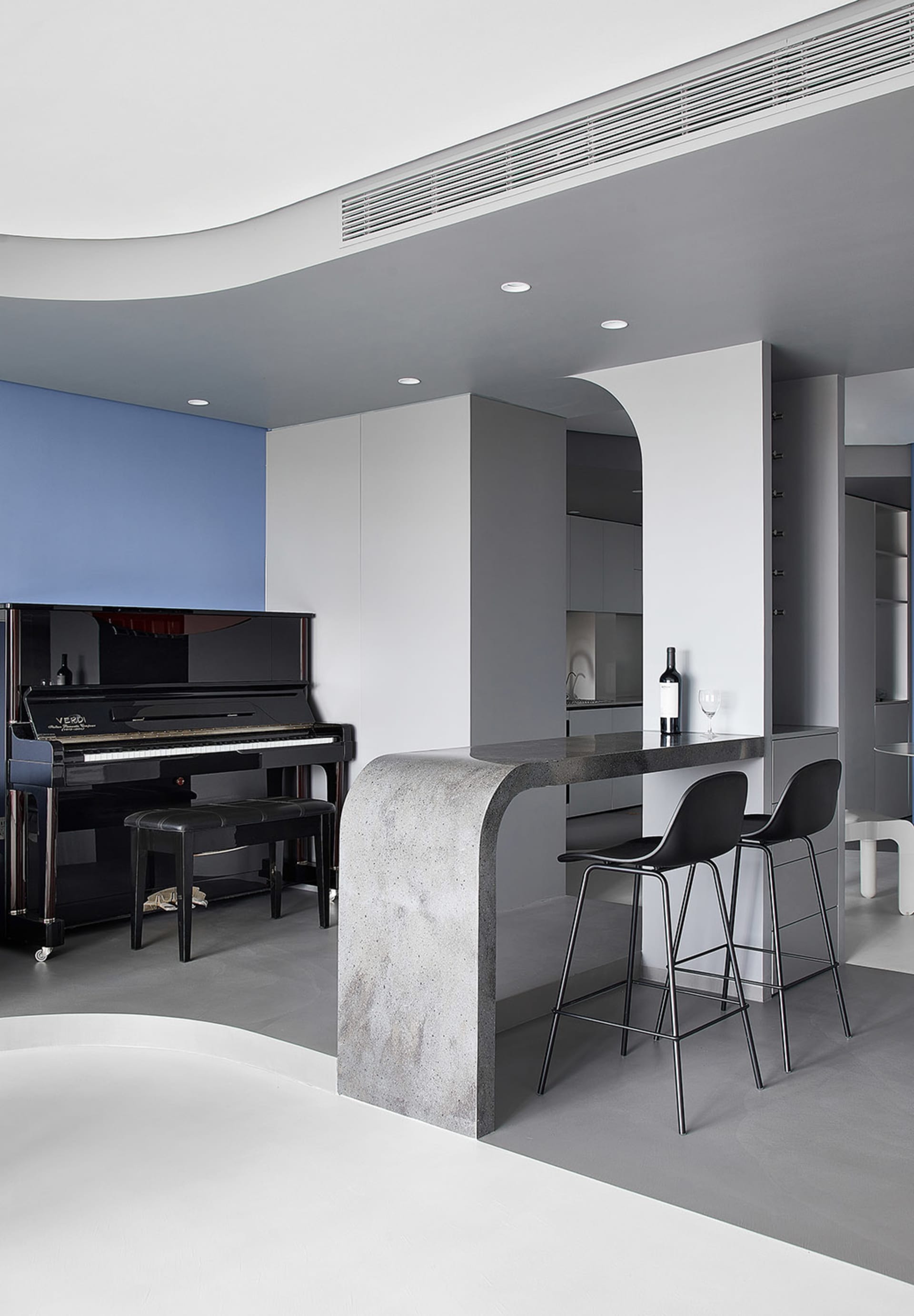 Modern living room featuring black piano and concrete kitchen island