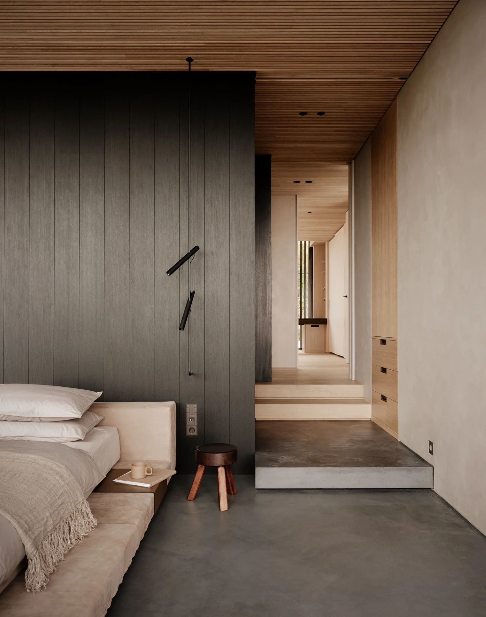 Modern minimalist bedroom featuring concrete floor and wooden accents, with a bed and minimalist furniture.