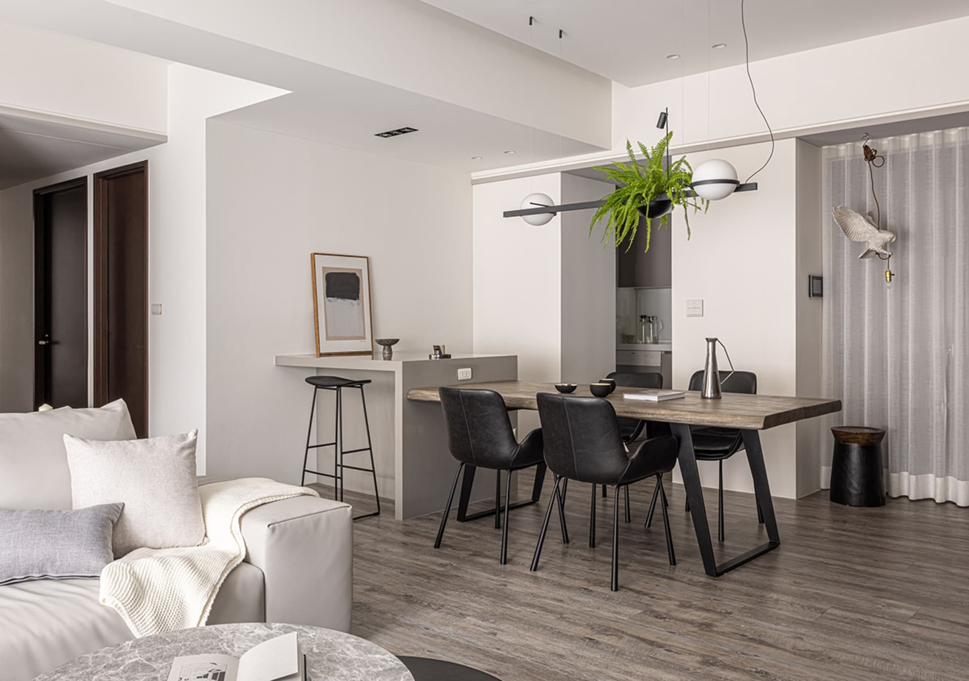 Modern minimalist living, dining, and kitchen space with sleek furniture and a neutral color palette.