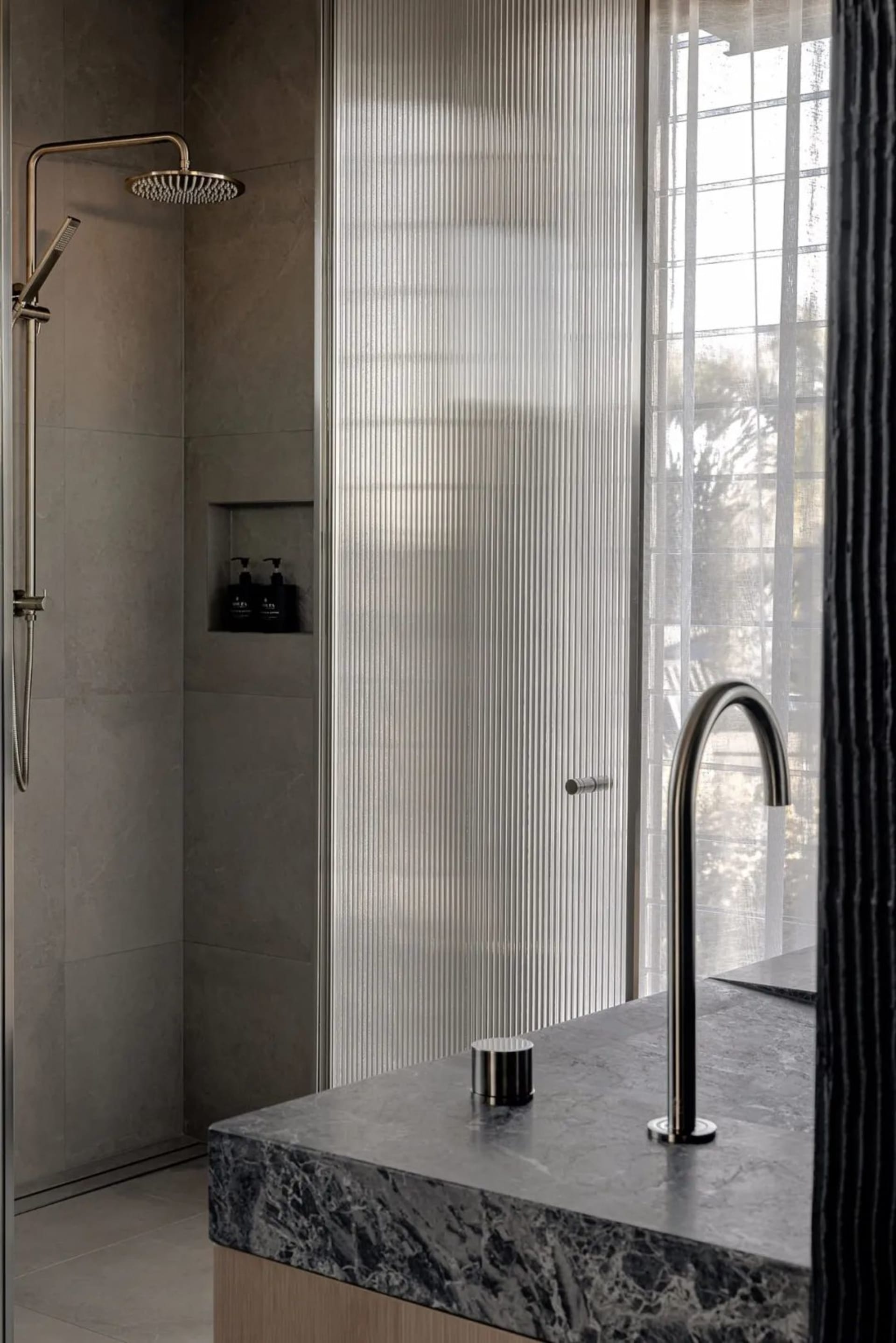 A contemporary bathroom featuring glass walls and a marble countertop.