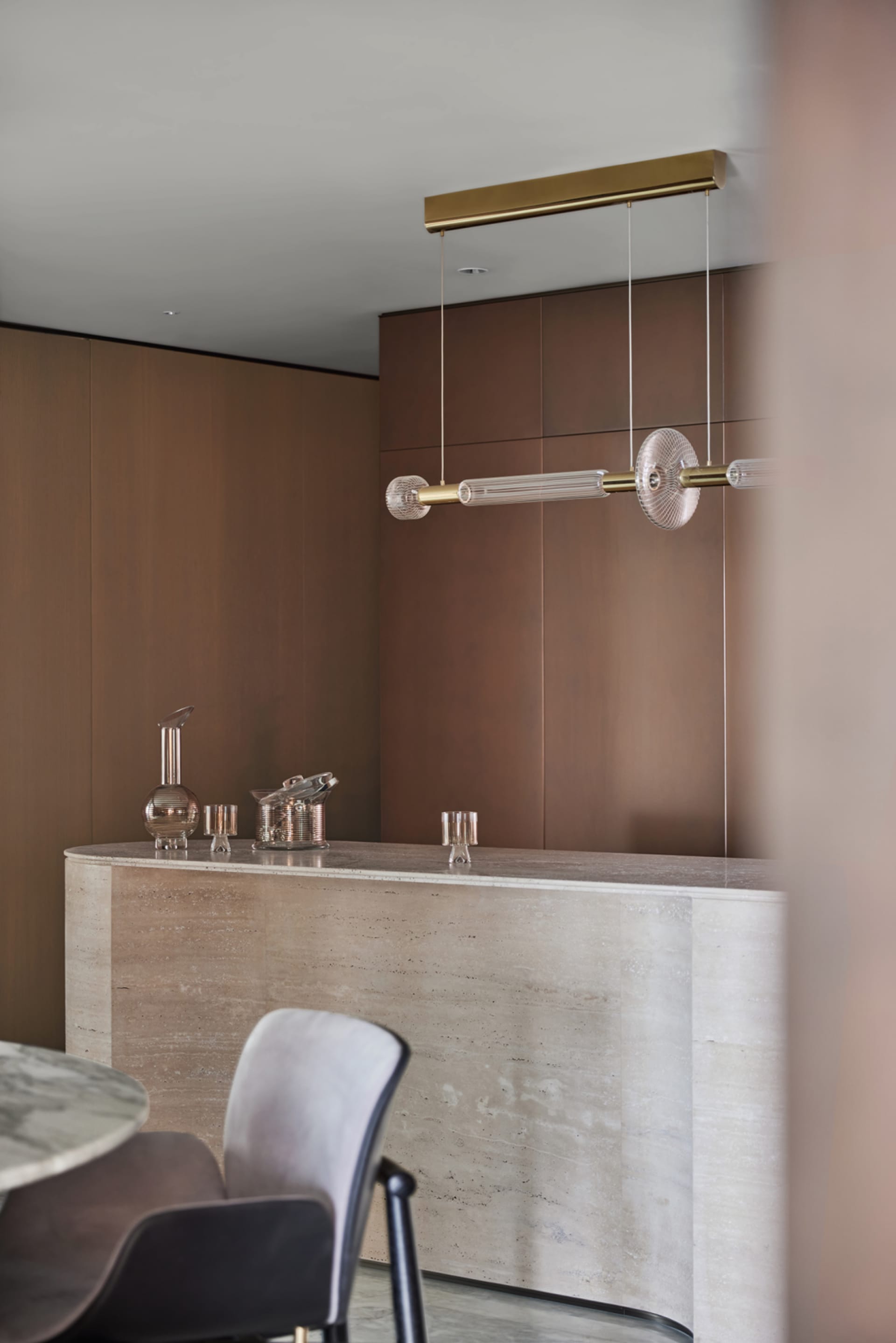 Modern bar counter featuring glass, brass, and marble materials.