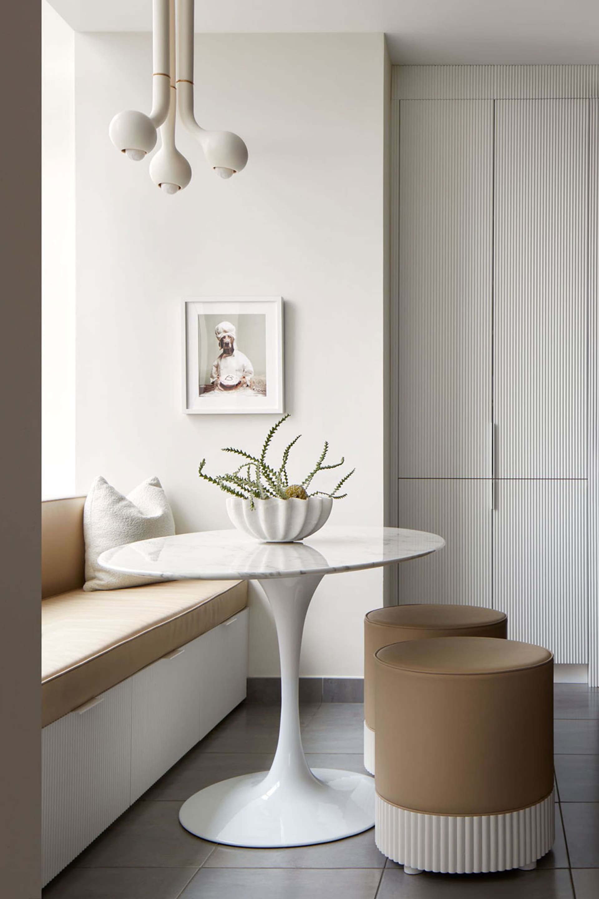 Modern kitchen area featuring a sleek, white marble table with a concrete base surrounded by comfortable seating, perfect for
