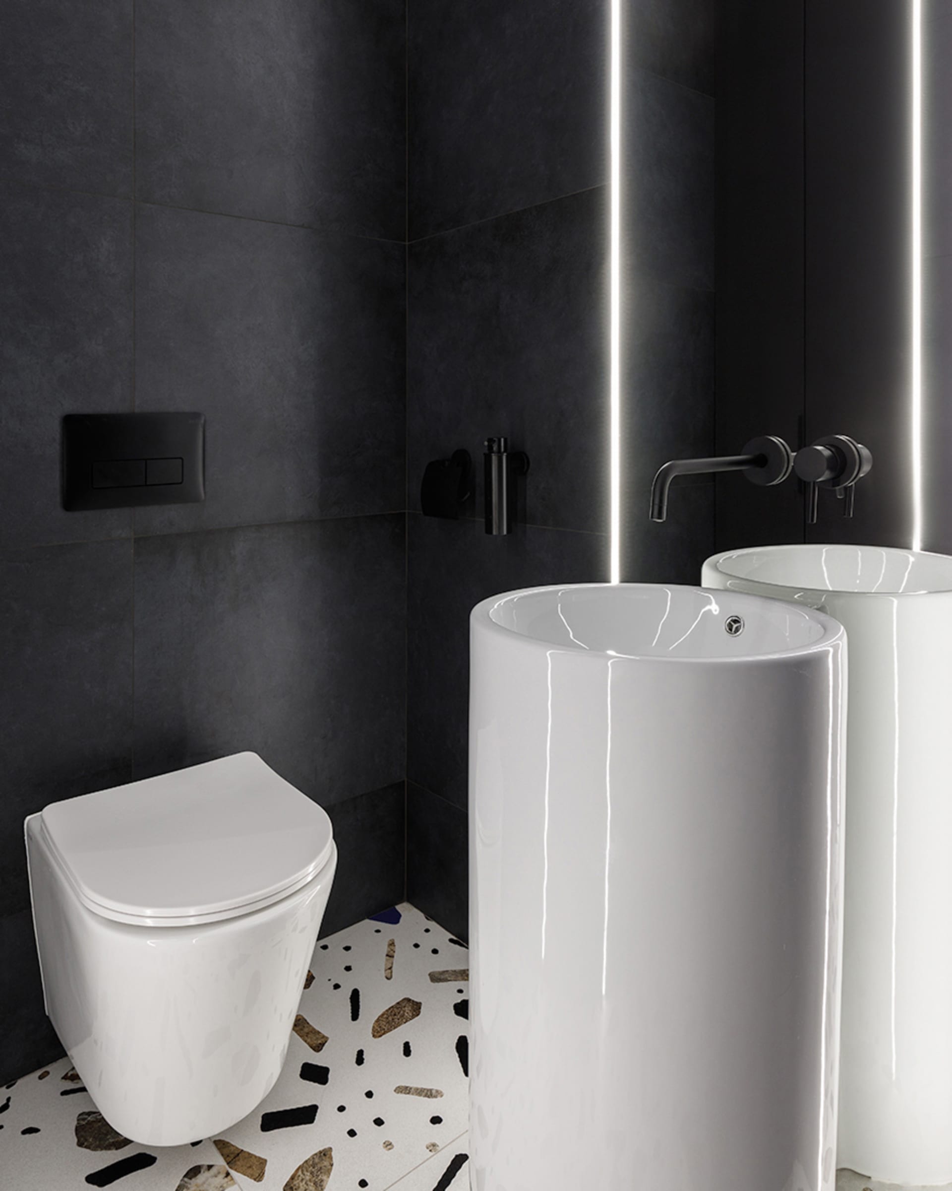 Modern minimalist bathroom with black ceramic tiles and a white freestanding sink with a terrazzo floor.