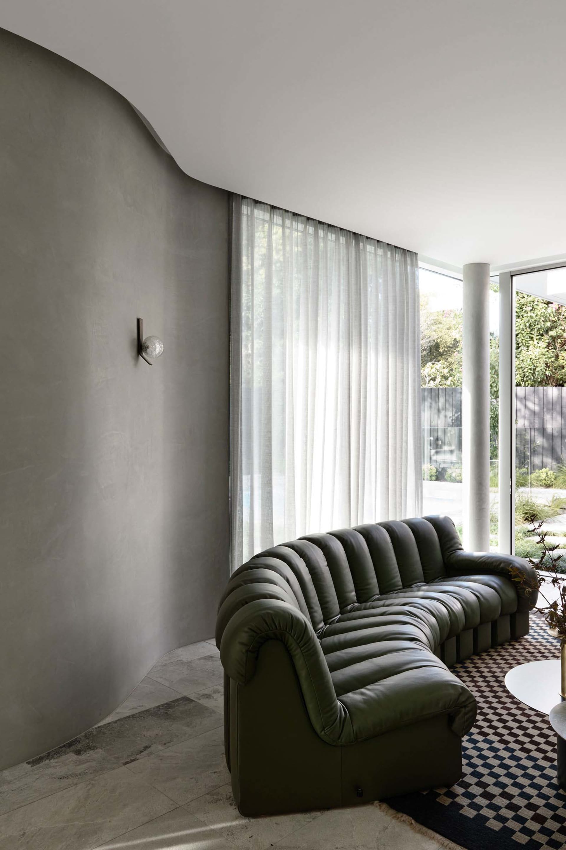 A modern sofa upholstered in green leather with a textured surface, positioned in a well-lit residential space.
