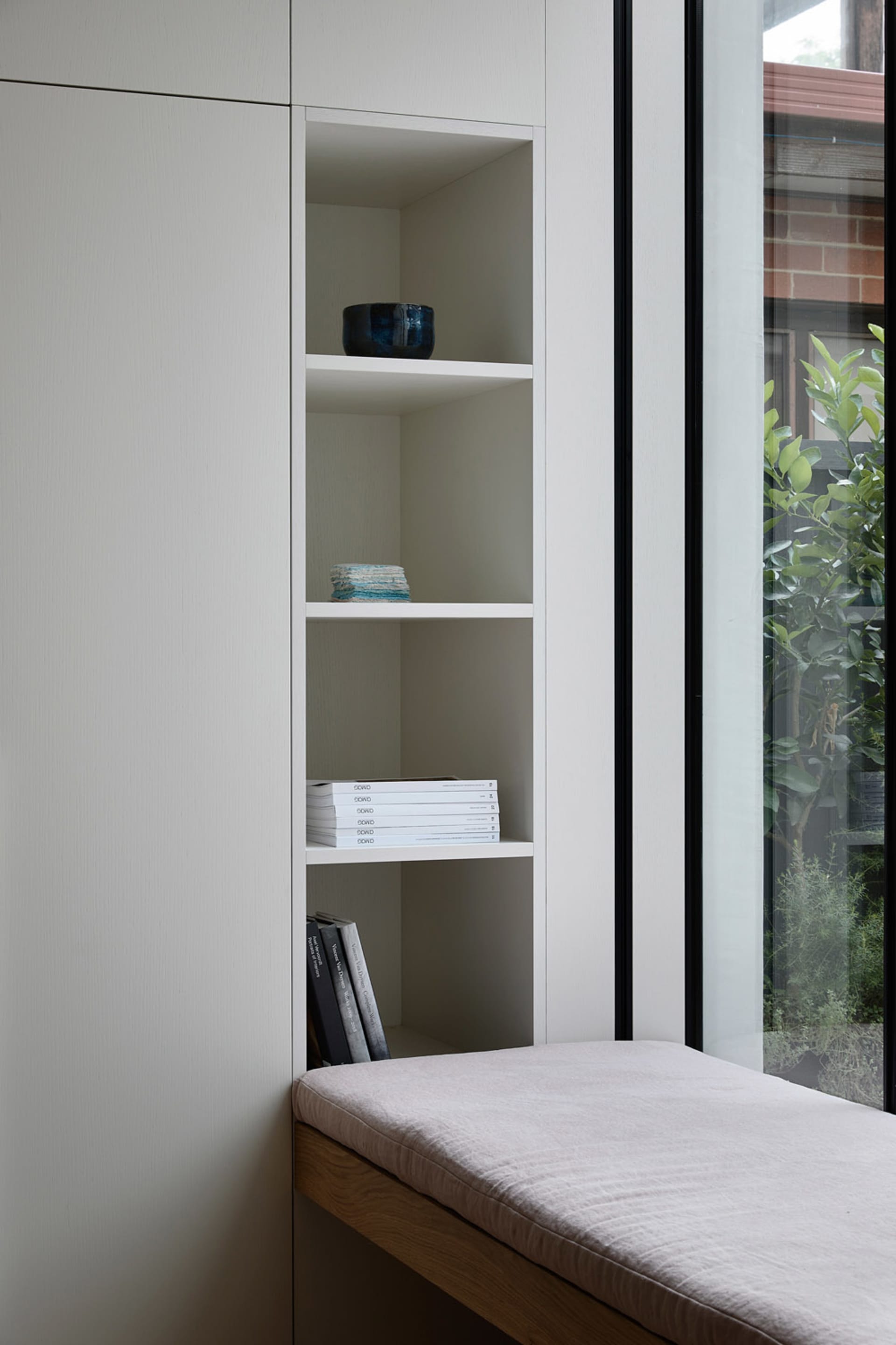 Minimalist interior design featuring a sleek granite bookshelf with neatly organized books and decorative items.