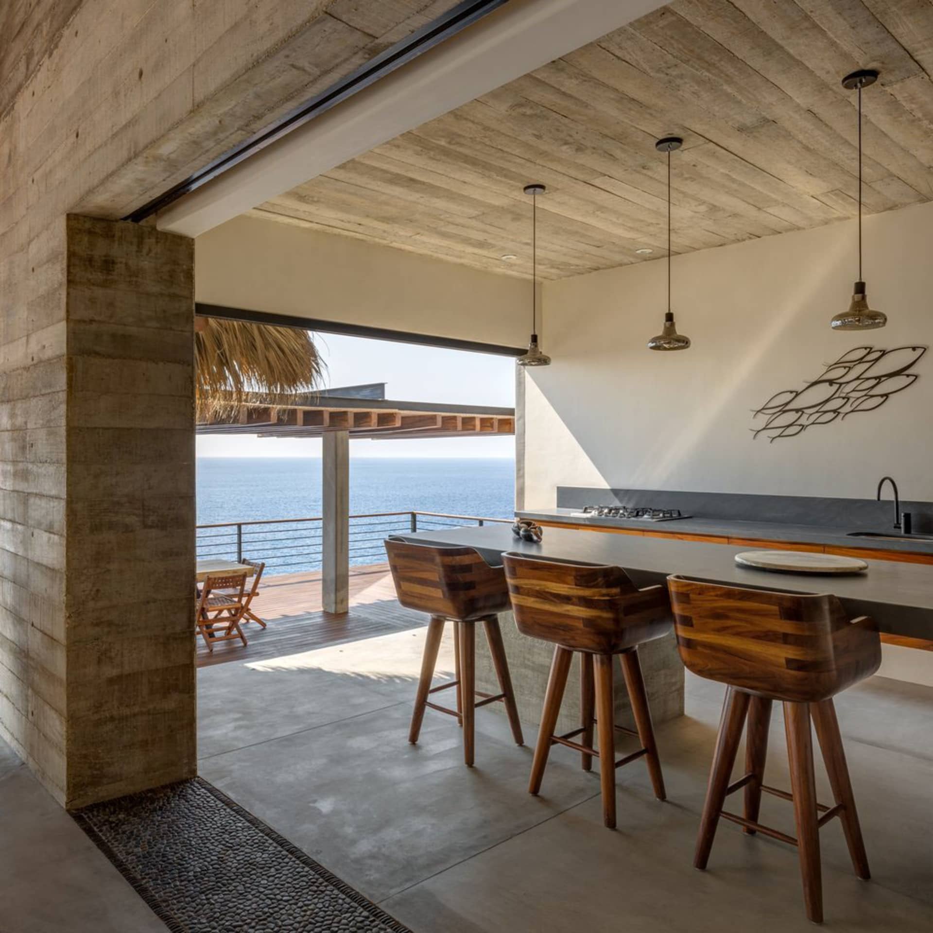 Modern minimalist residential kitchen featuring concrete and terrazzo materials with ocean views.